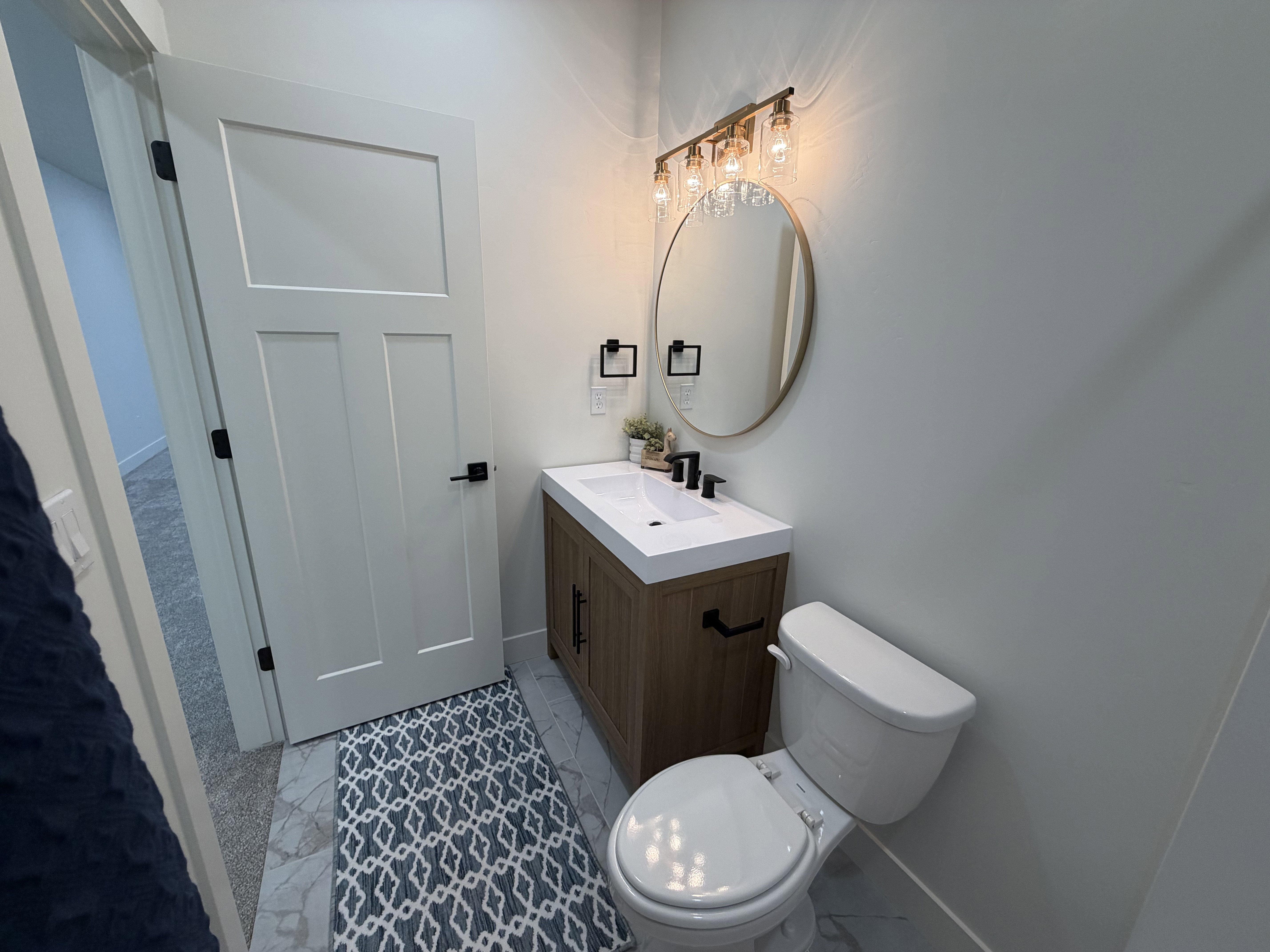 Powder room featuring a single-sink vanity with wood-finish cabinetry, a white countertop, and a matte black faucet
