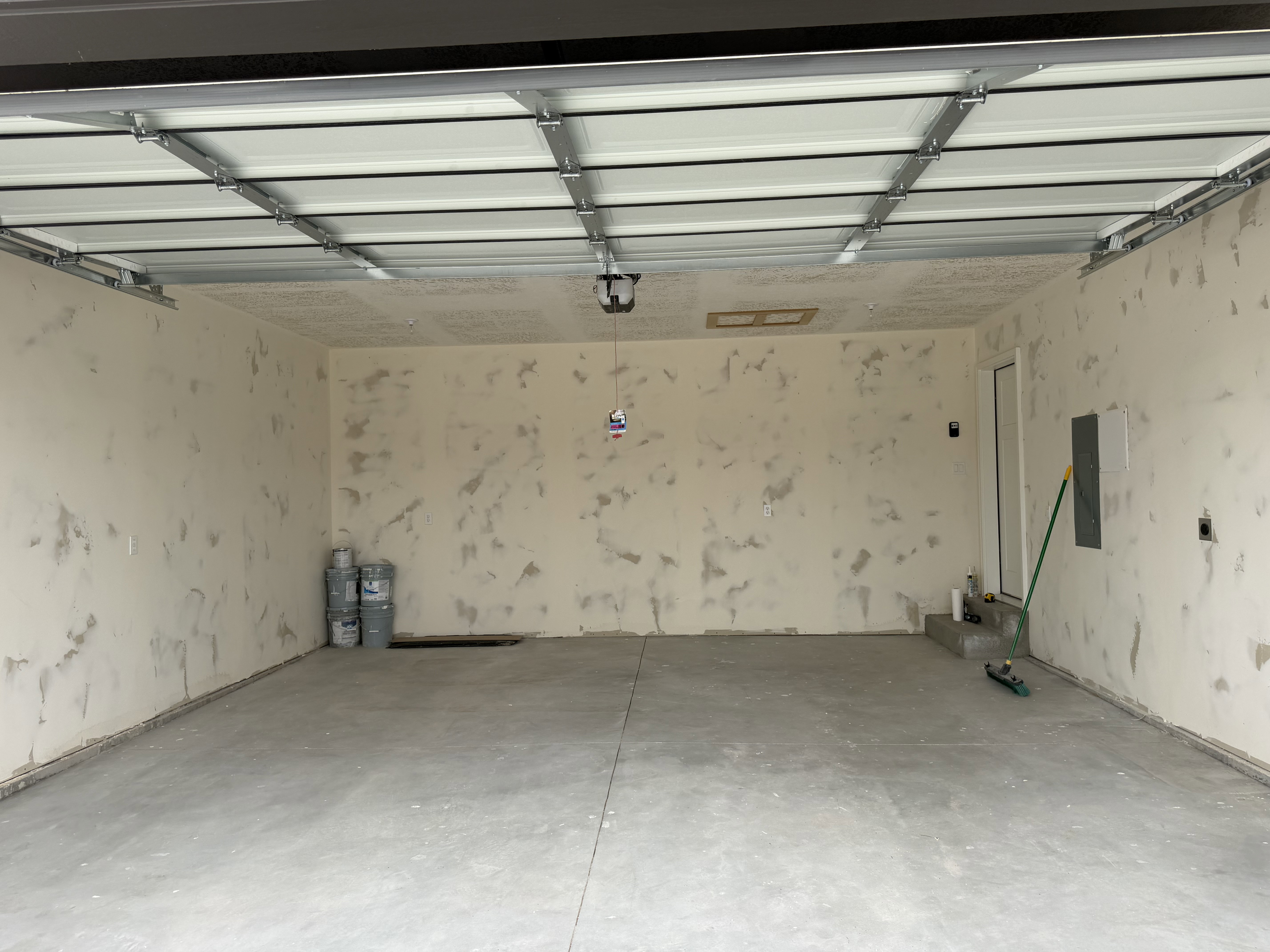 Spacious garage with concrete flooring, automatic garage door, and interior access door