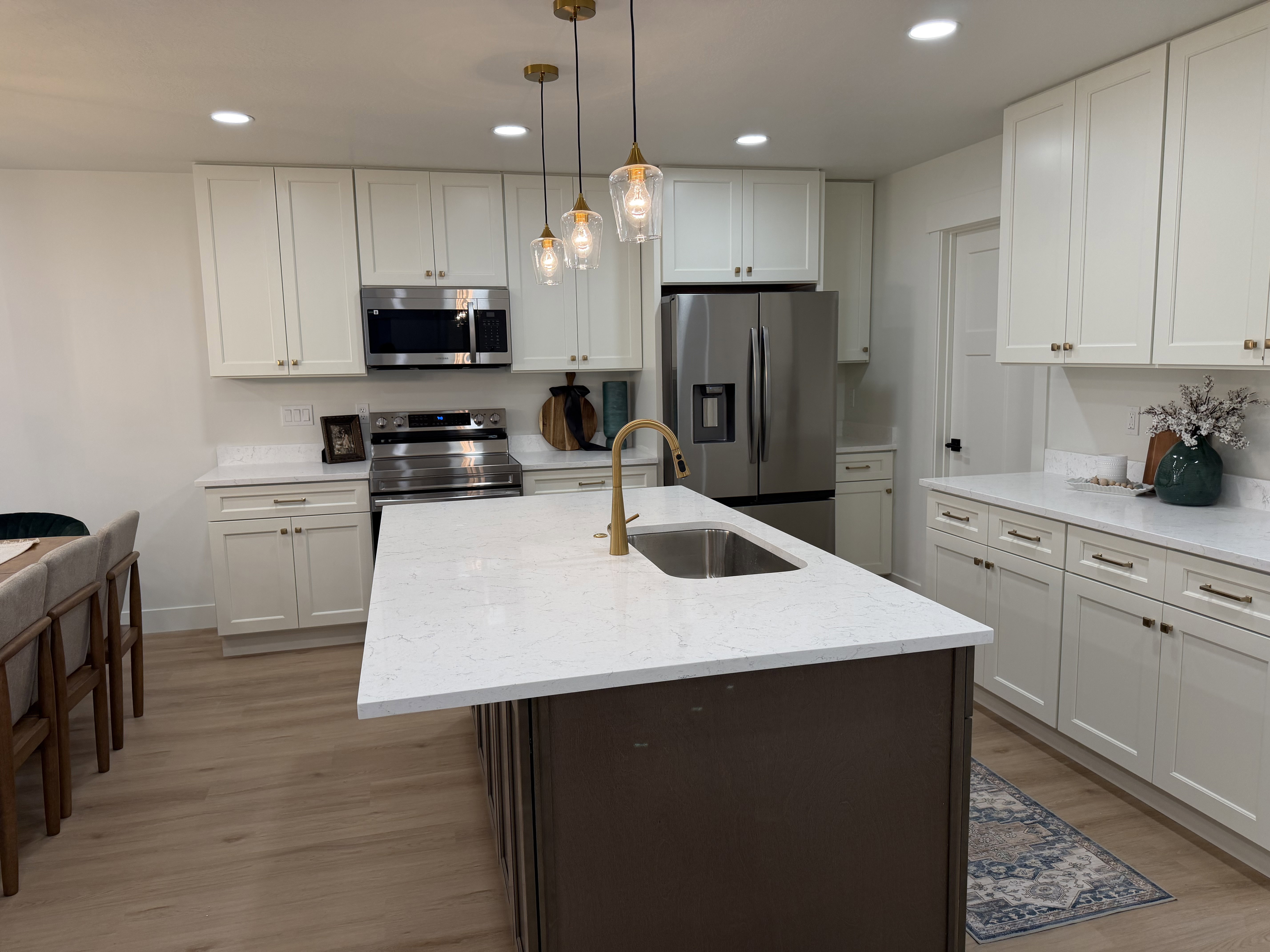 Kitchen featuring a central island with an undermount sink, brass faucet, and white countertop