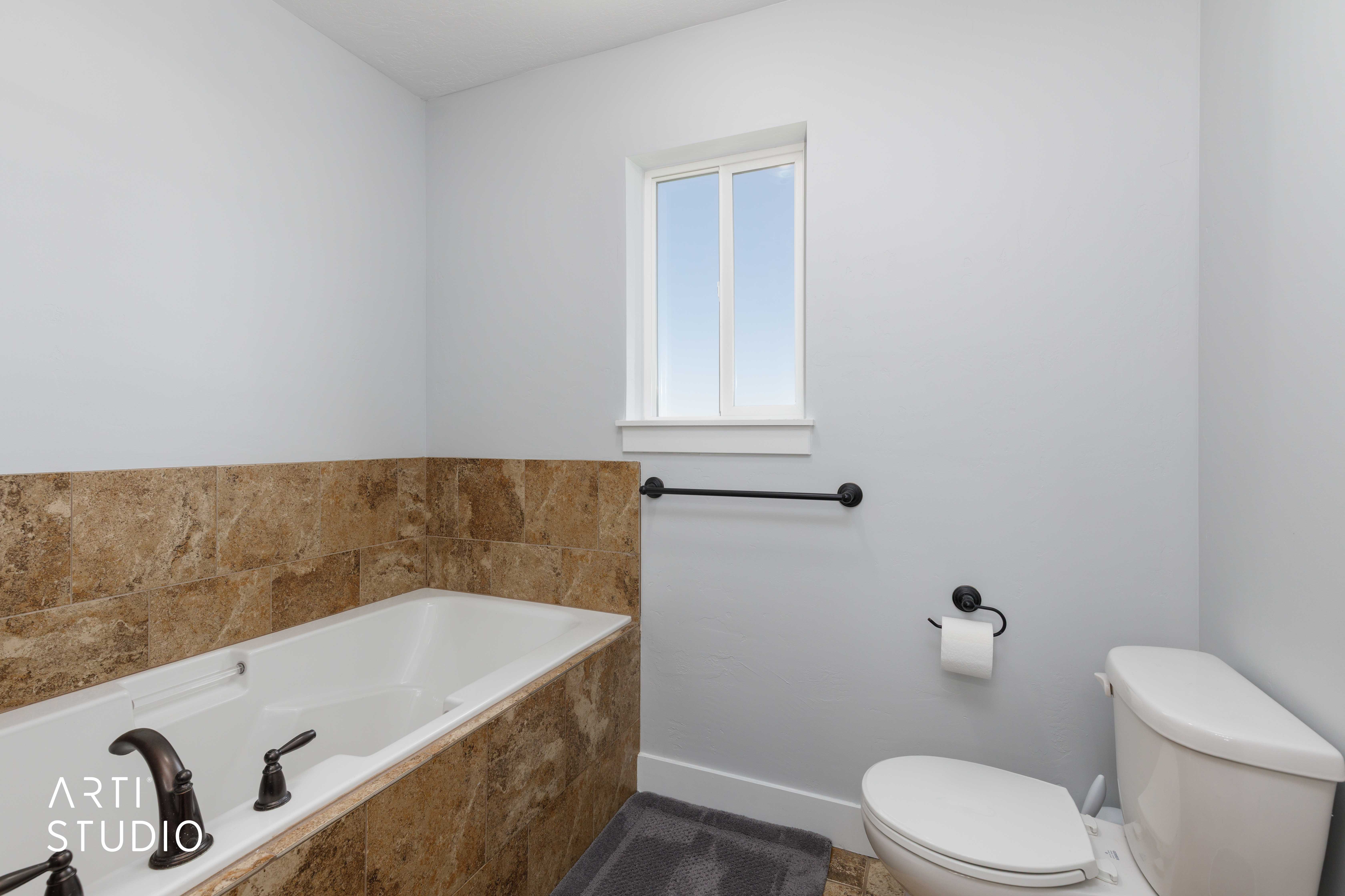 Soaking tub with bronze fixtures, surrounded by earth-toned tile