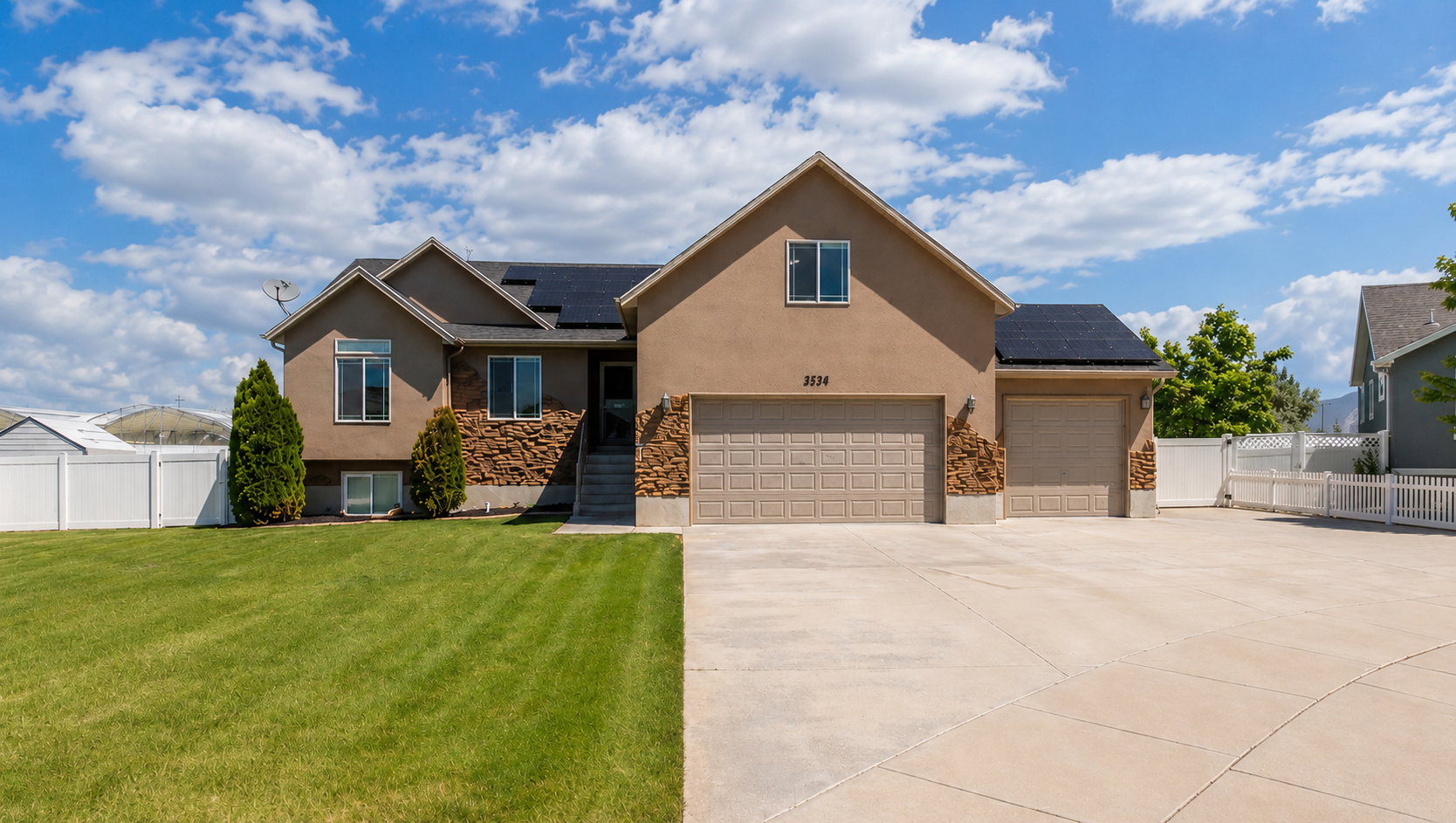 Two-story residence featuring a stucco and stone veneer facade, multiple roof-mounted solar panels, and a concrete driveway