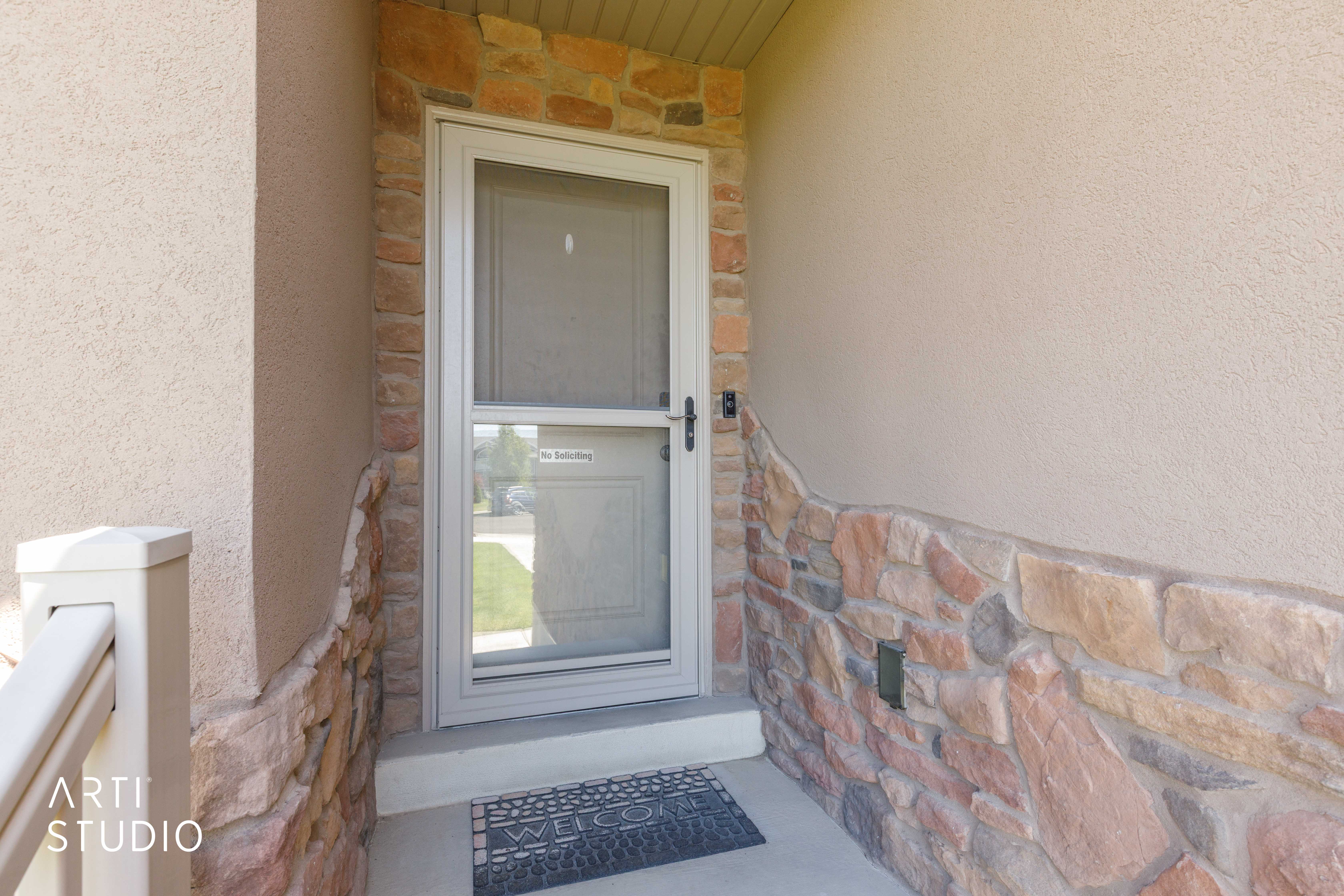 Entryway with a security screen door, stone veneer detailing, stucco siding, and a concrete porch