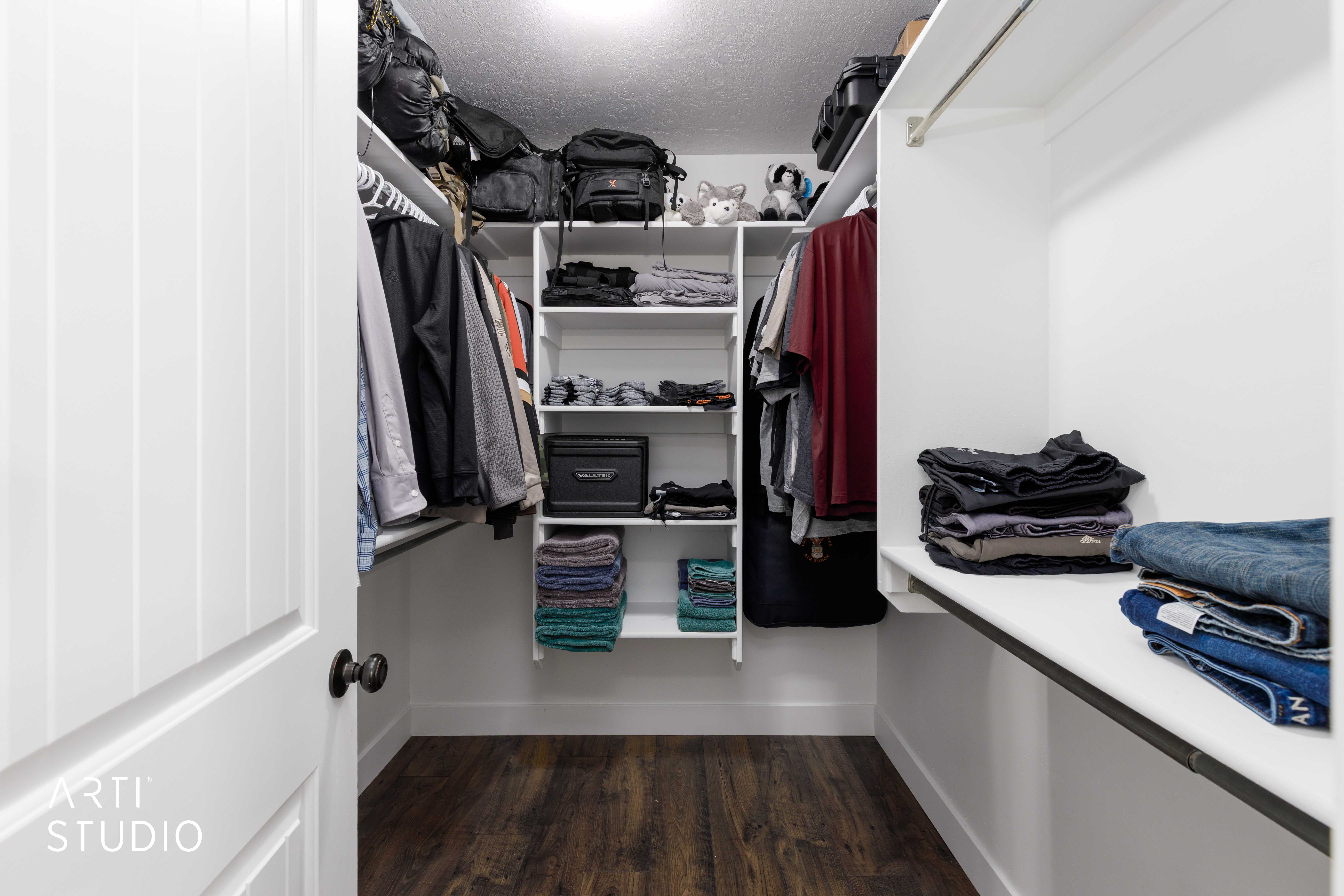 Walk-in closet featuring custom white shelving, ample hanging rods, and wood-finish flooring