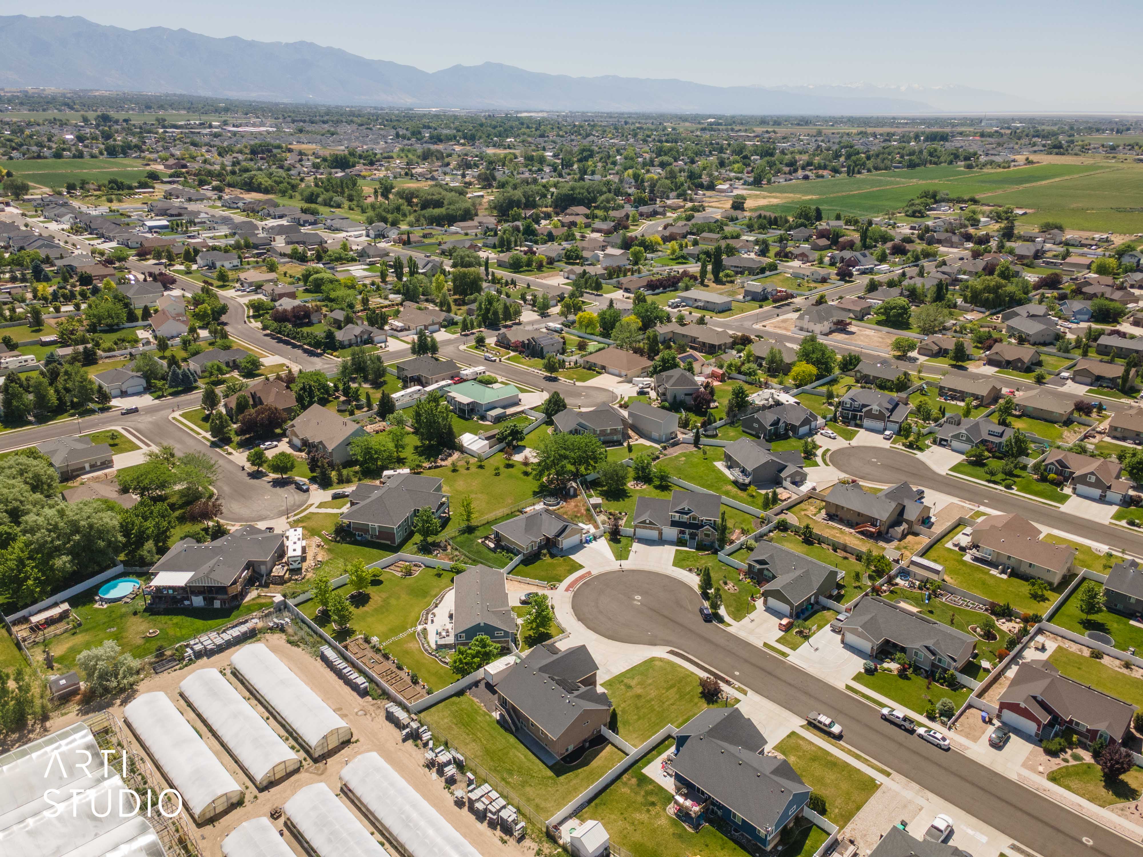 Expansive aerial perspective showcasing a residential neighborhood with varied architectural styles, mature landscaping, and mountain backdrop
