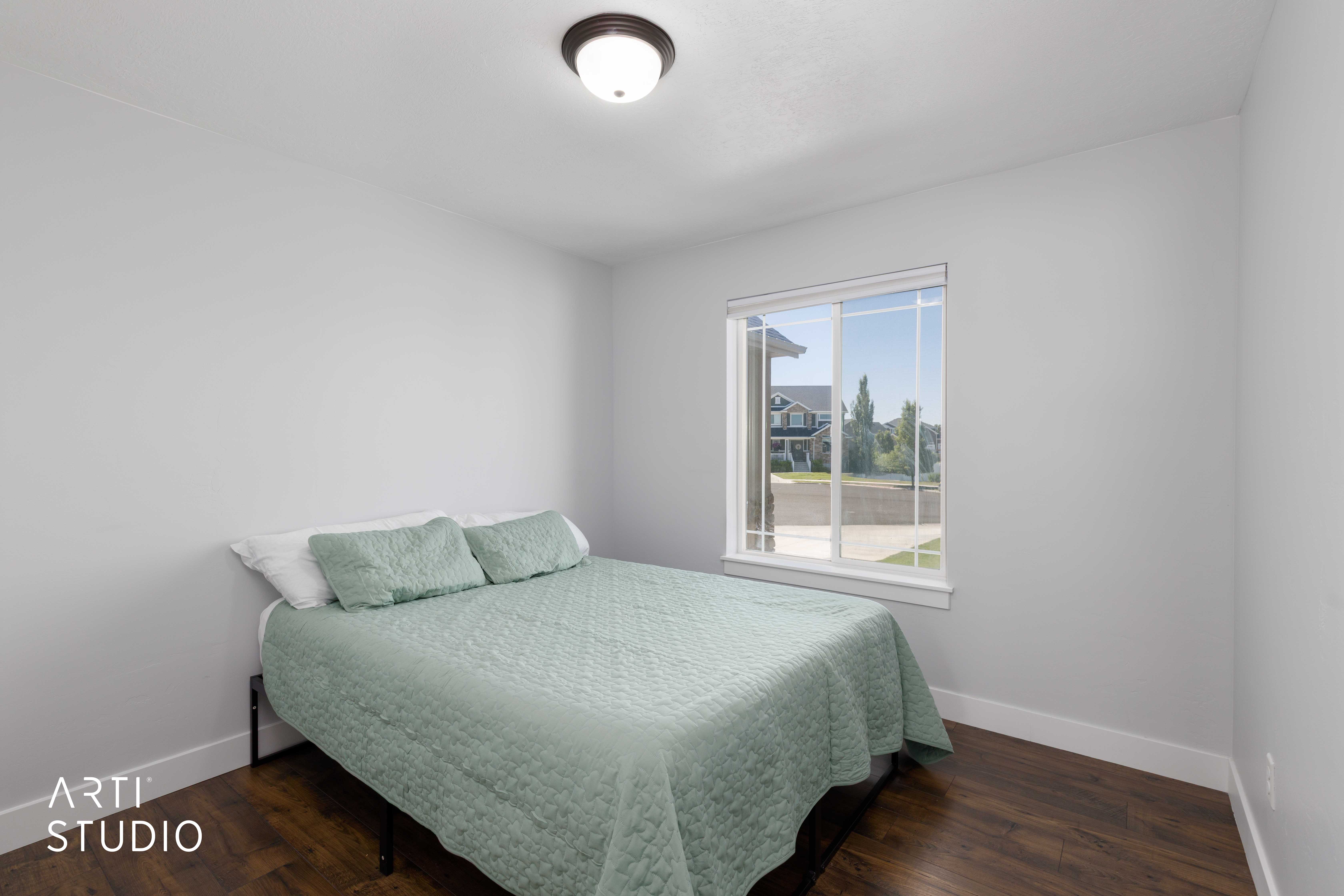 Bedroom featuring wood-finish flooring, light gray walls, a flush-mount ceiling light, and a white-framed window