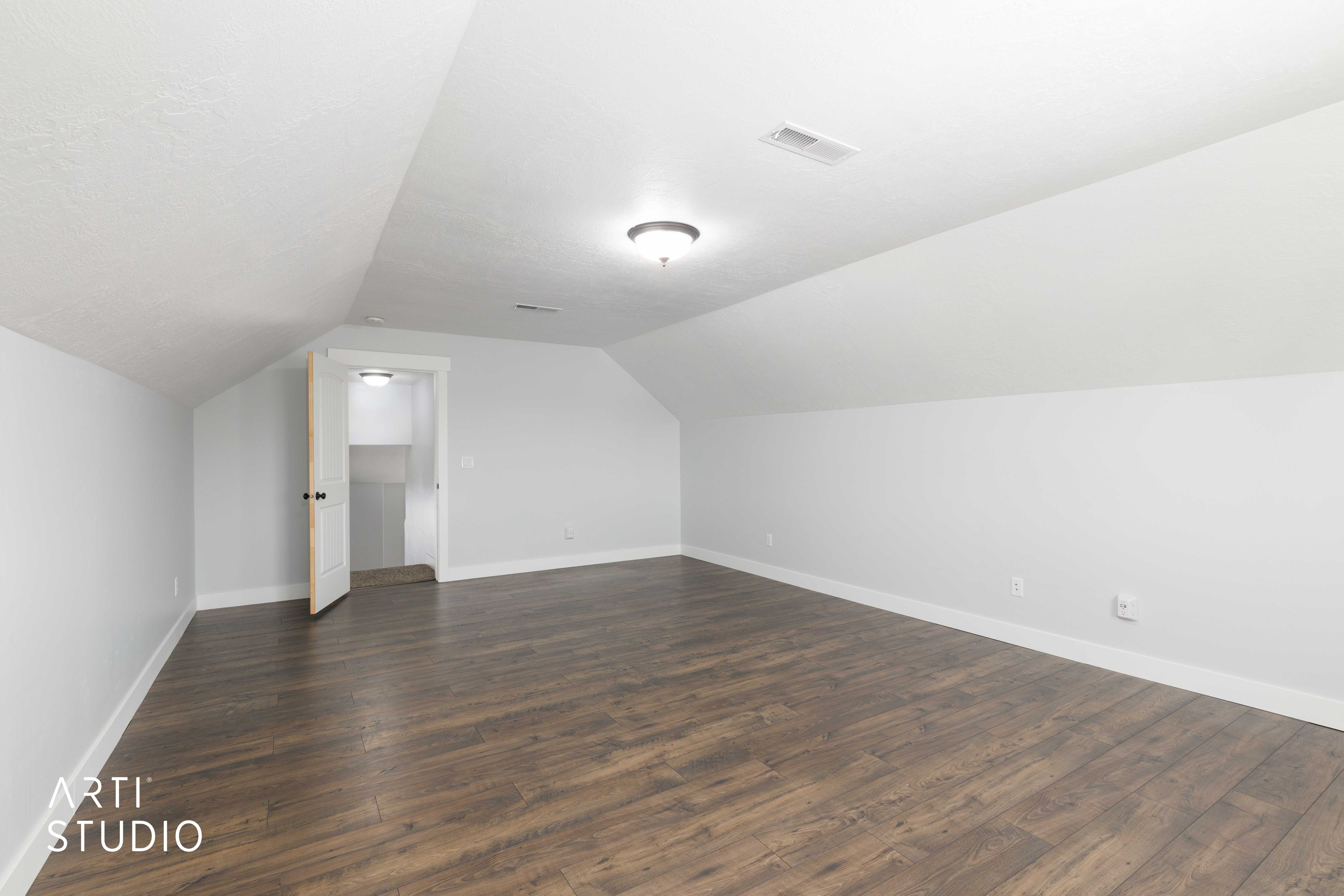 Spacious room featuring wood-finish flooring, white walls, and a recessed ceiling light