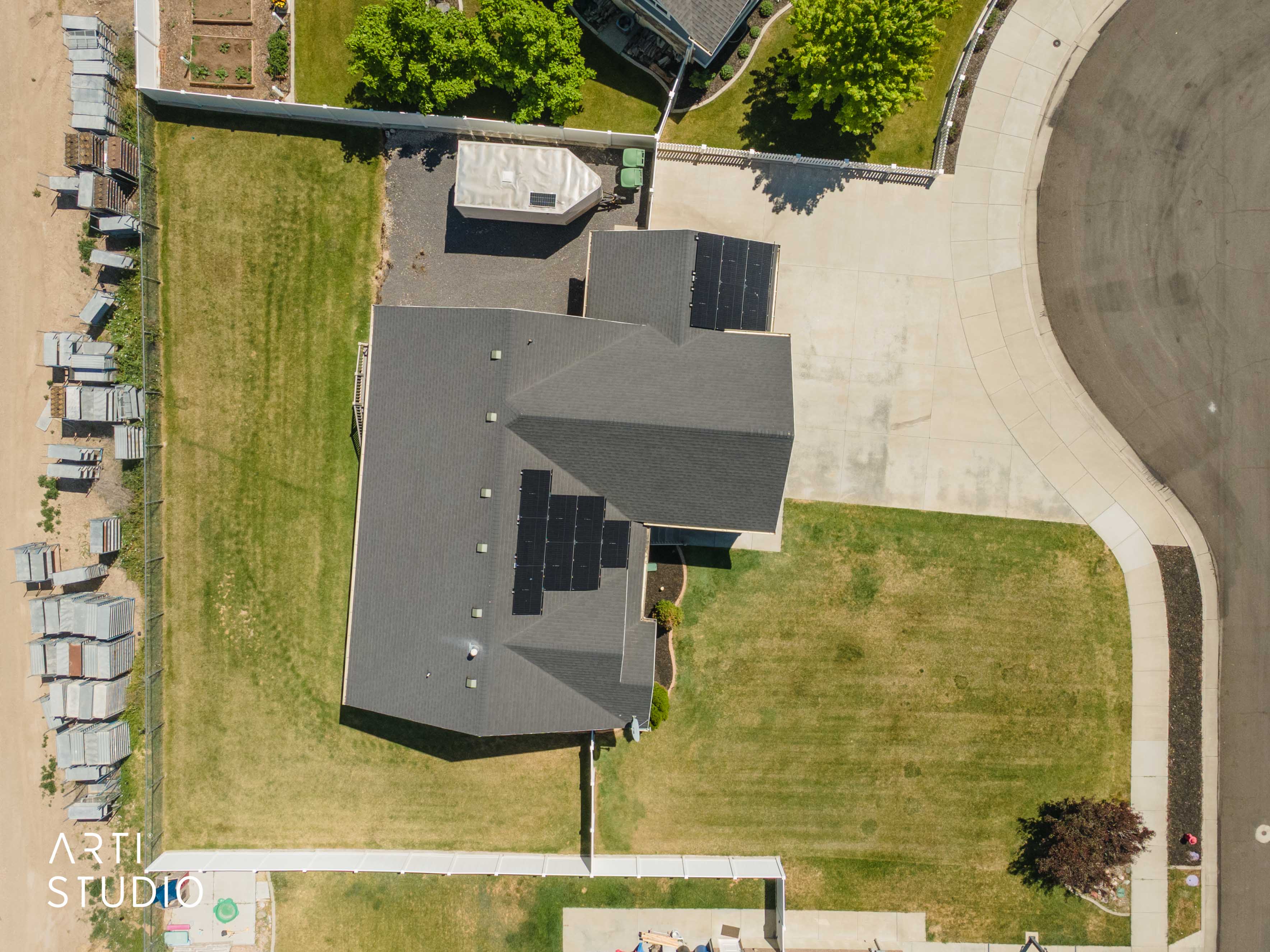 Aerial perspective showcasing the property's expansive lot, dark shingle roof, and multiple solar panel installations