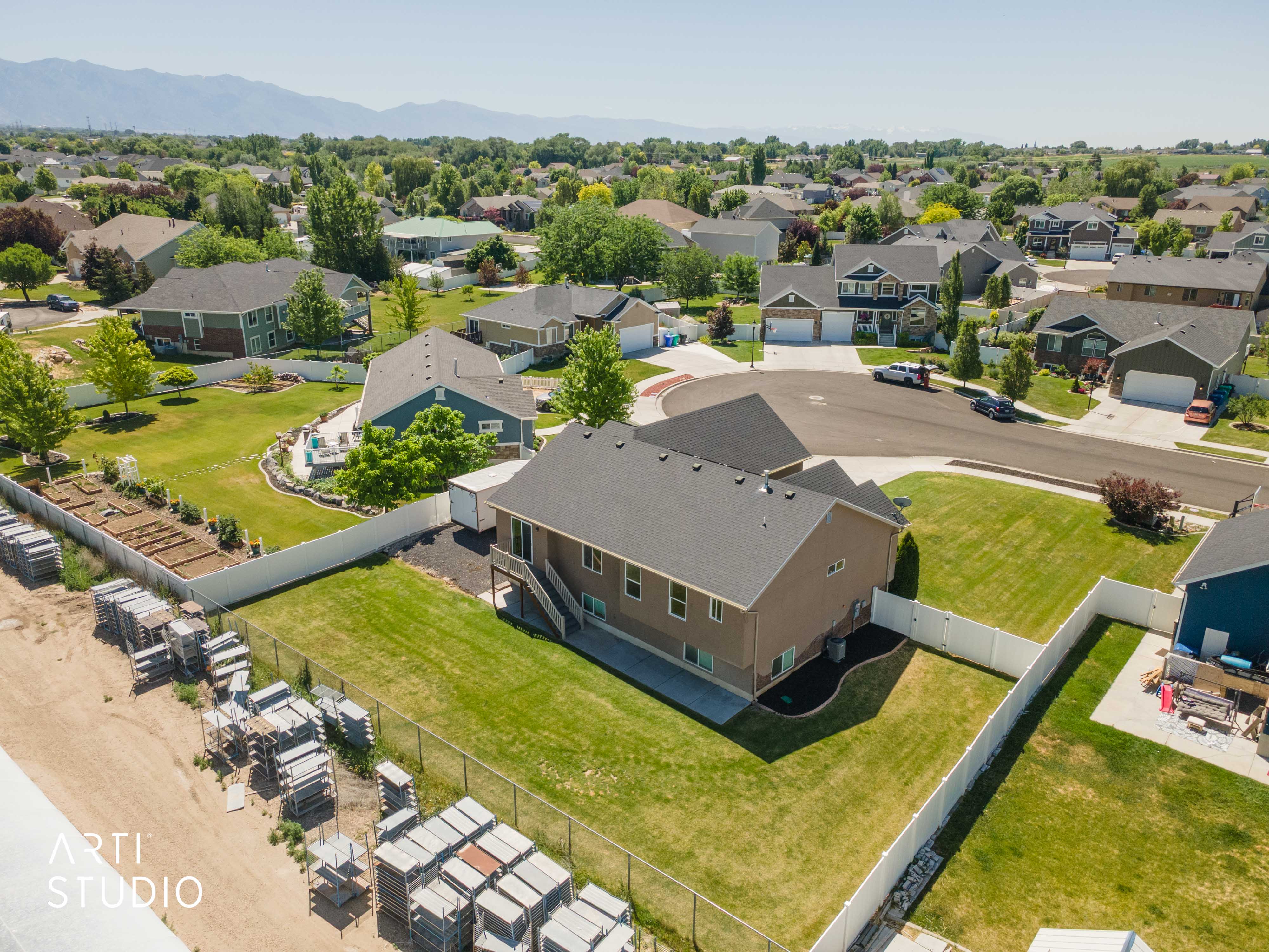 Spacious property featuring a large green lawn, privacy fencing, and mountain range backdrop