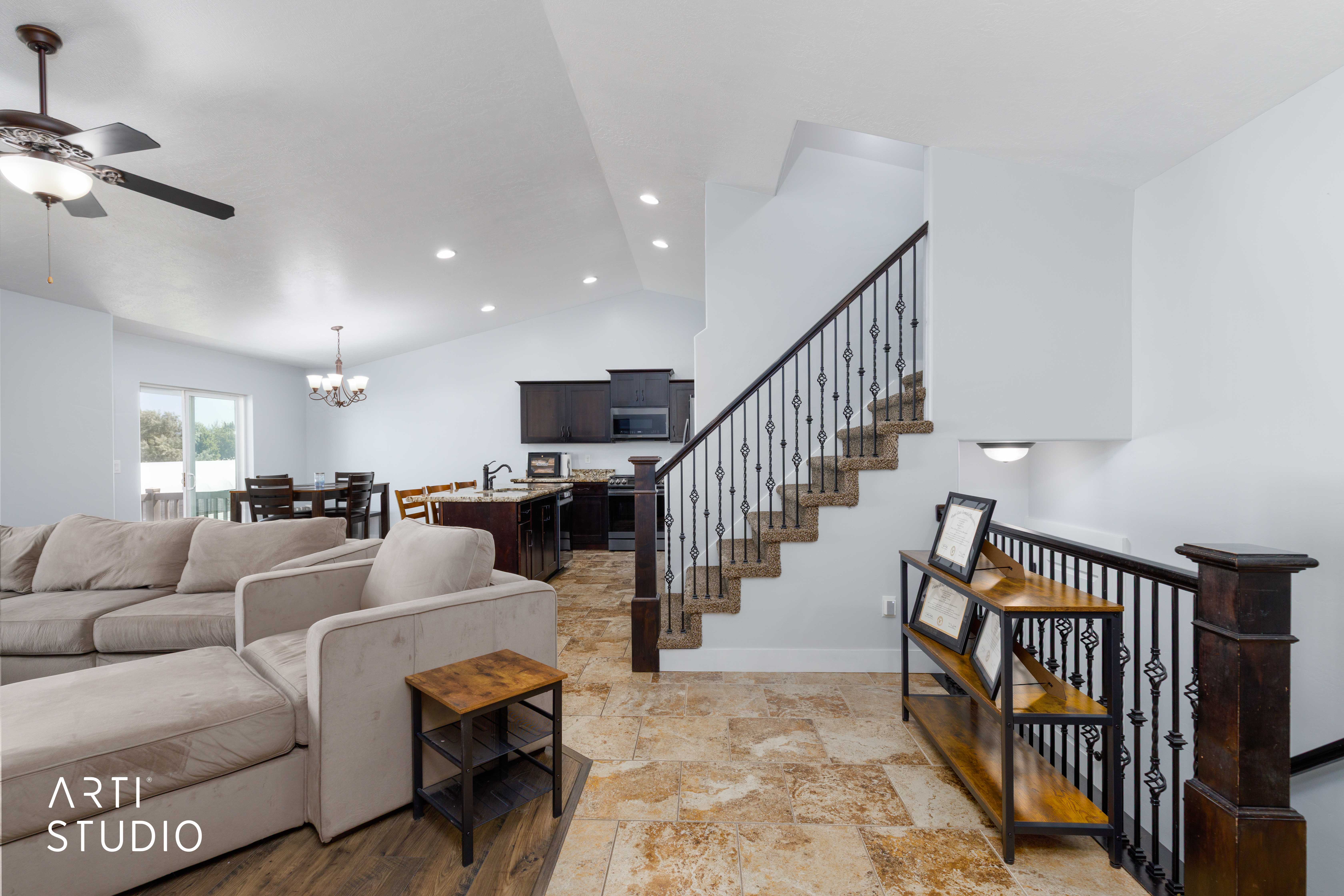 Open-concept interior featuring light-toned flooring, a staircase with wrought iron balusters, recessed lighting, and a dining area with a sliding glass door