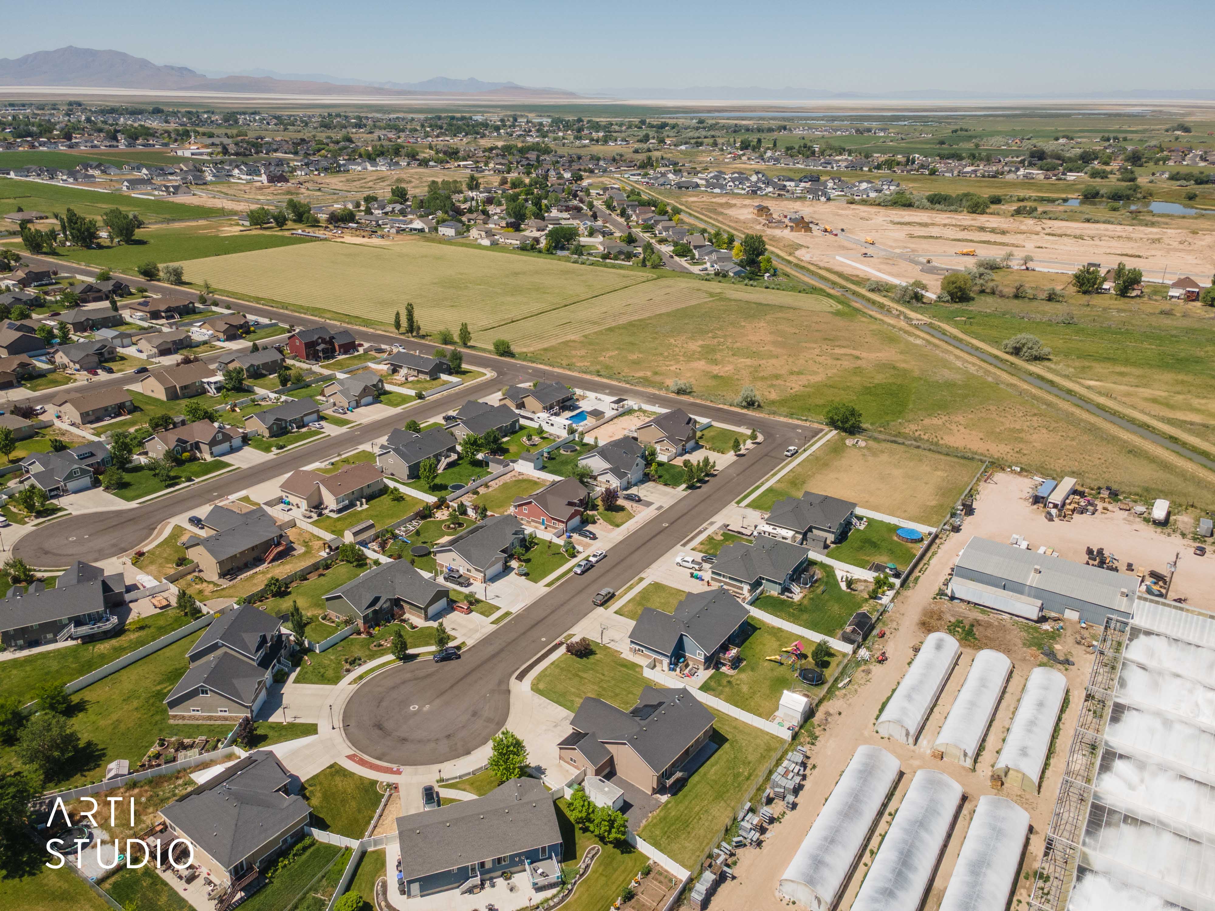 Aerial perspective showcasing a residential development with cul-de-sac streets, individual homes with dark-toned roofs, and green lawns