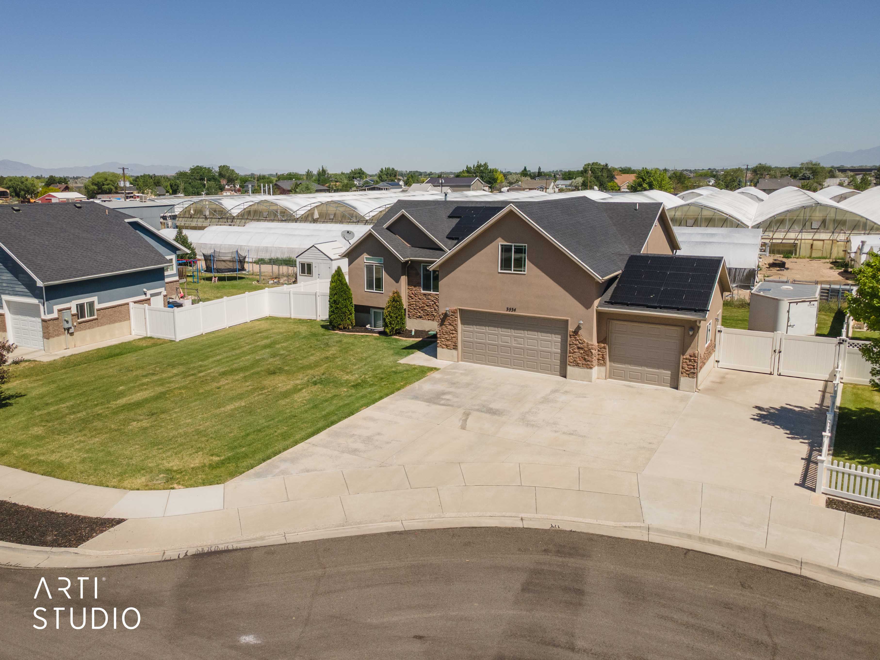 Two-story stucco residence featuring a dual-bay garage, a single-bay garage, and solar panels