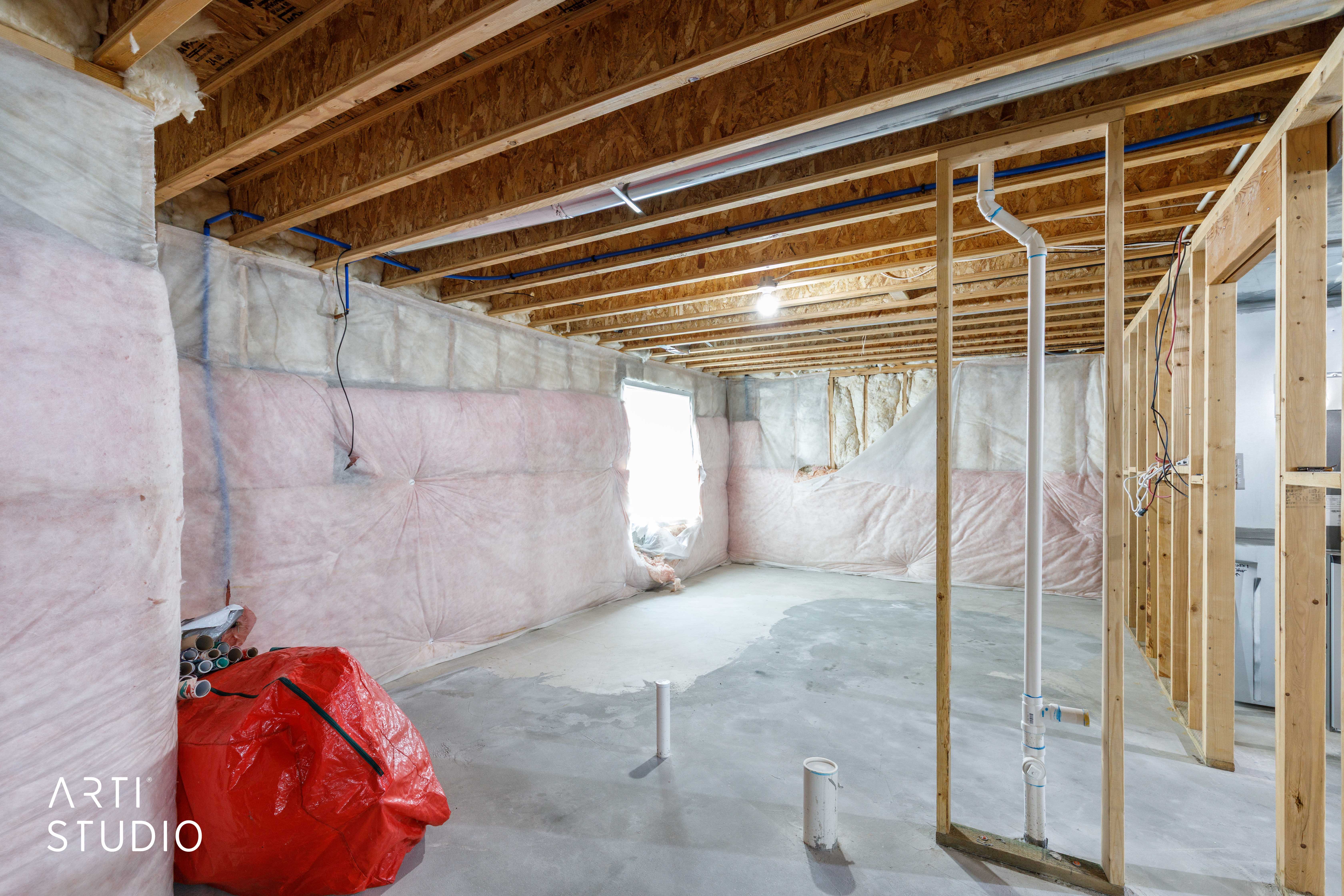 Unfinished basement space featuring exposed wood joists and subflooring, framed walls, and a concrete floor