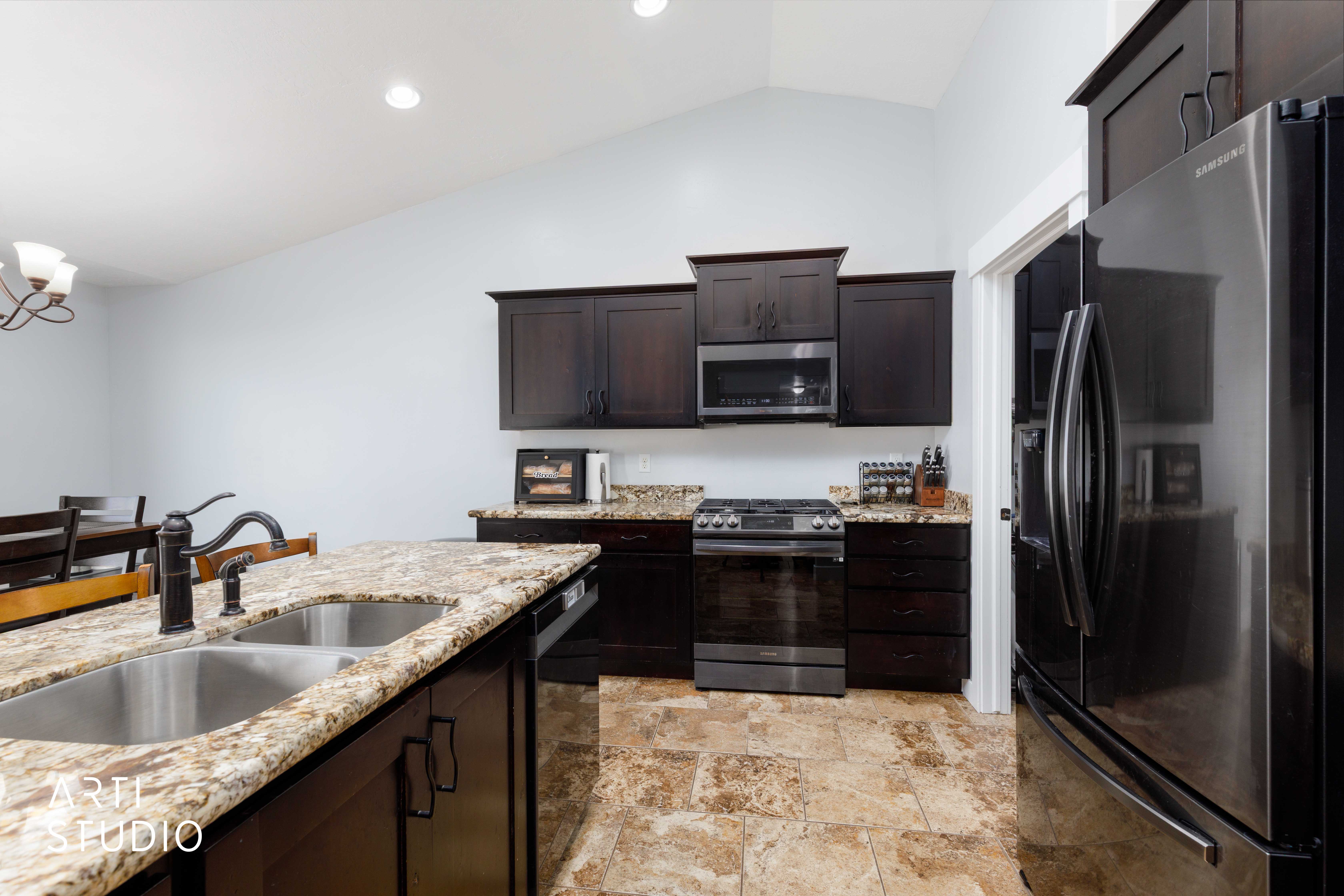 Kitchen featuring dark wood cabinetry, stainless steel appliances, granite countertops, and tile flooring