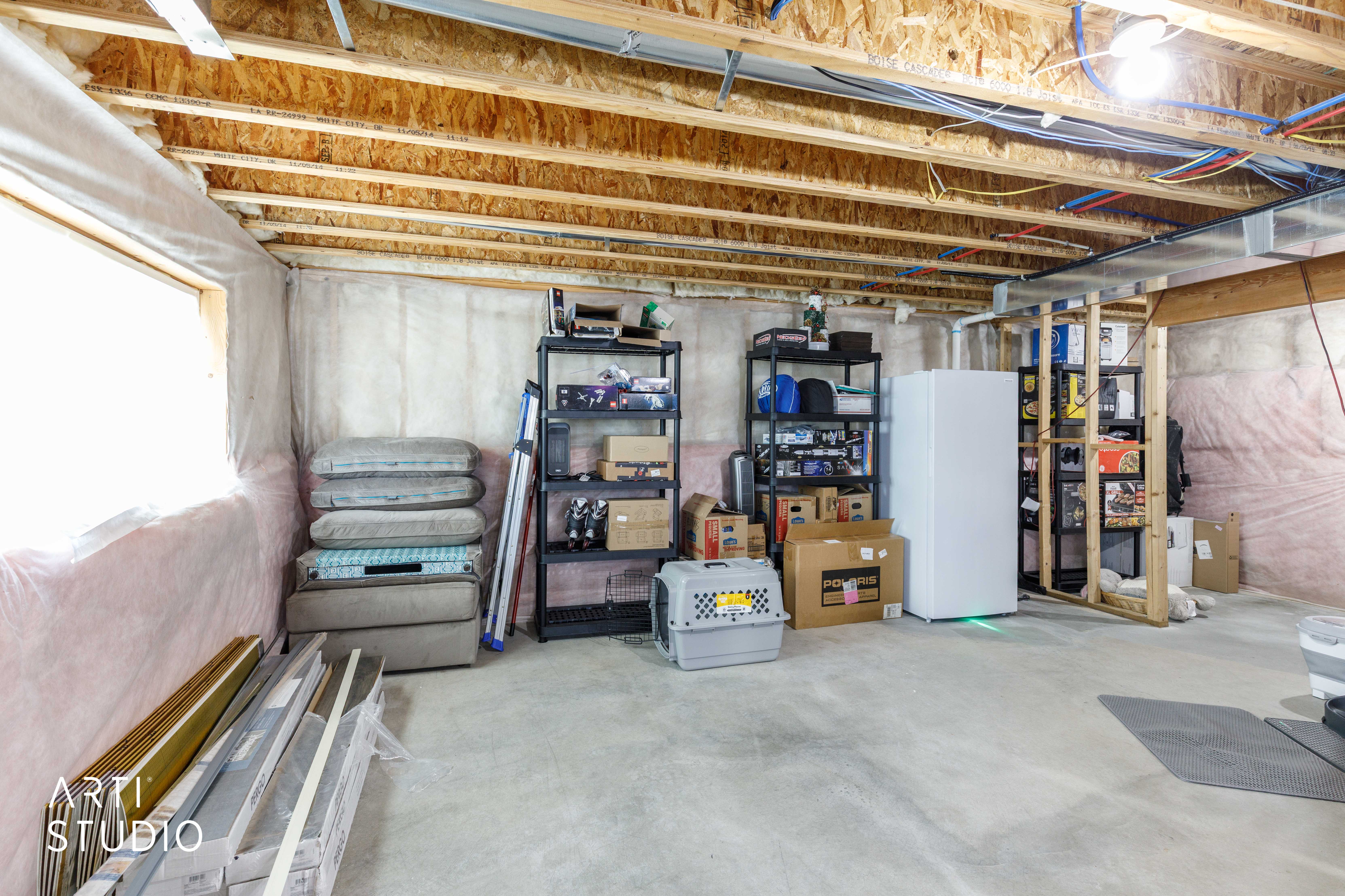 Open basement space featuring concrete flooring, exposed wood joists, and a utility window
