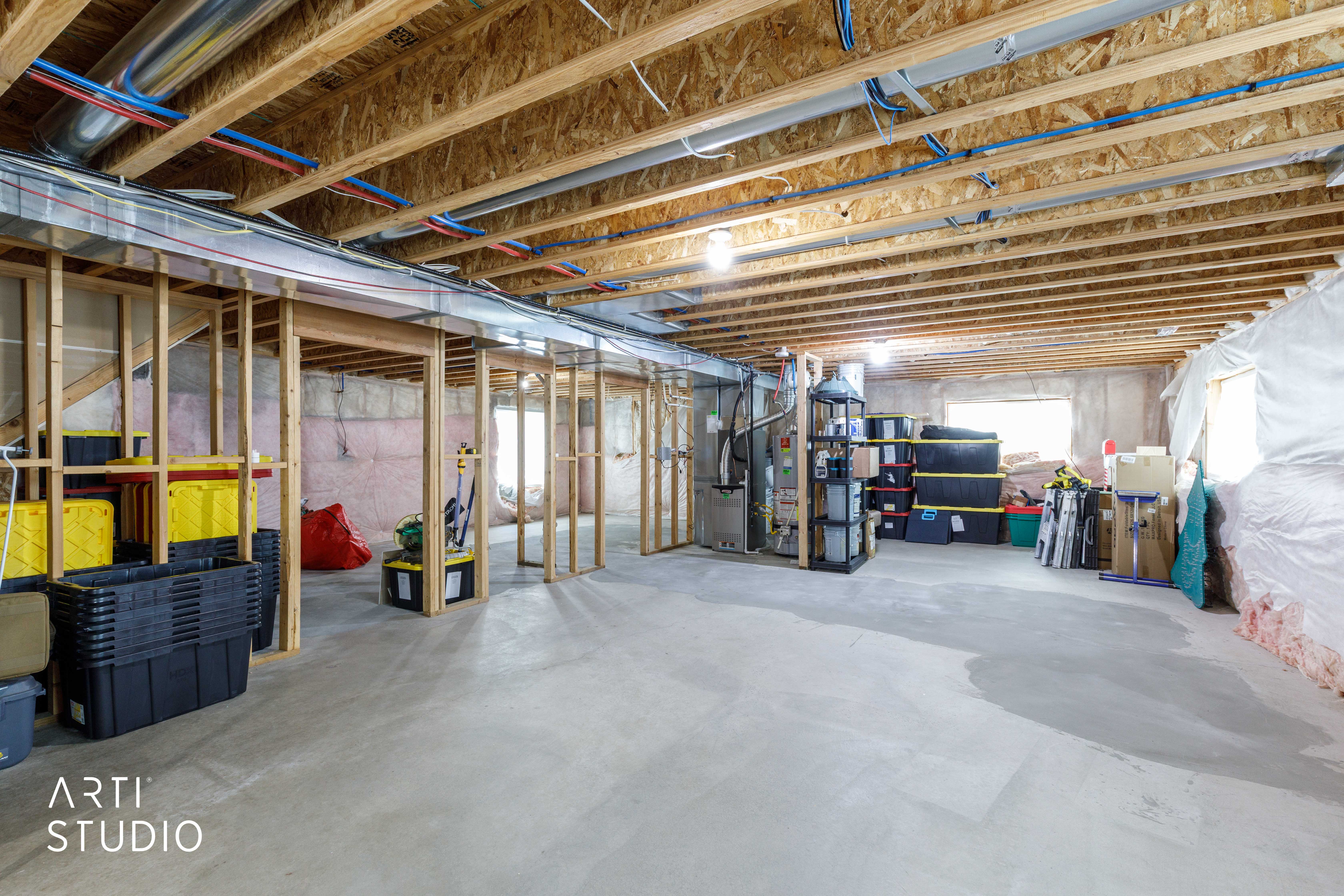 Unfinished basement featuring exposed wood joists, concrete flooring, framed wall sections, and multiple windows providing natural light