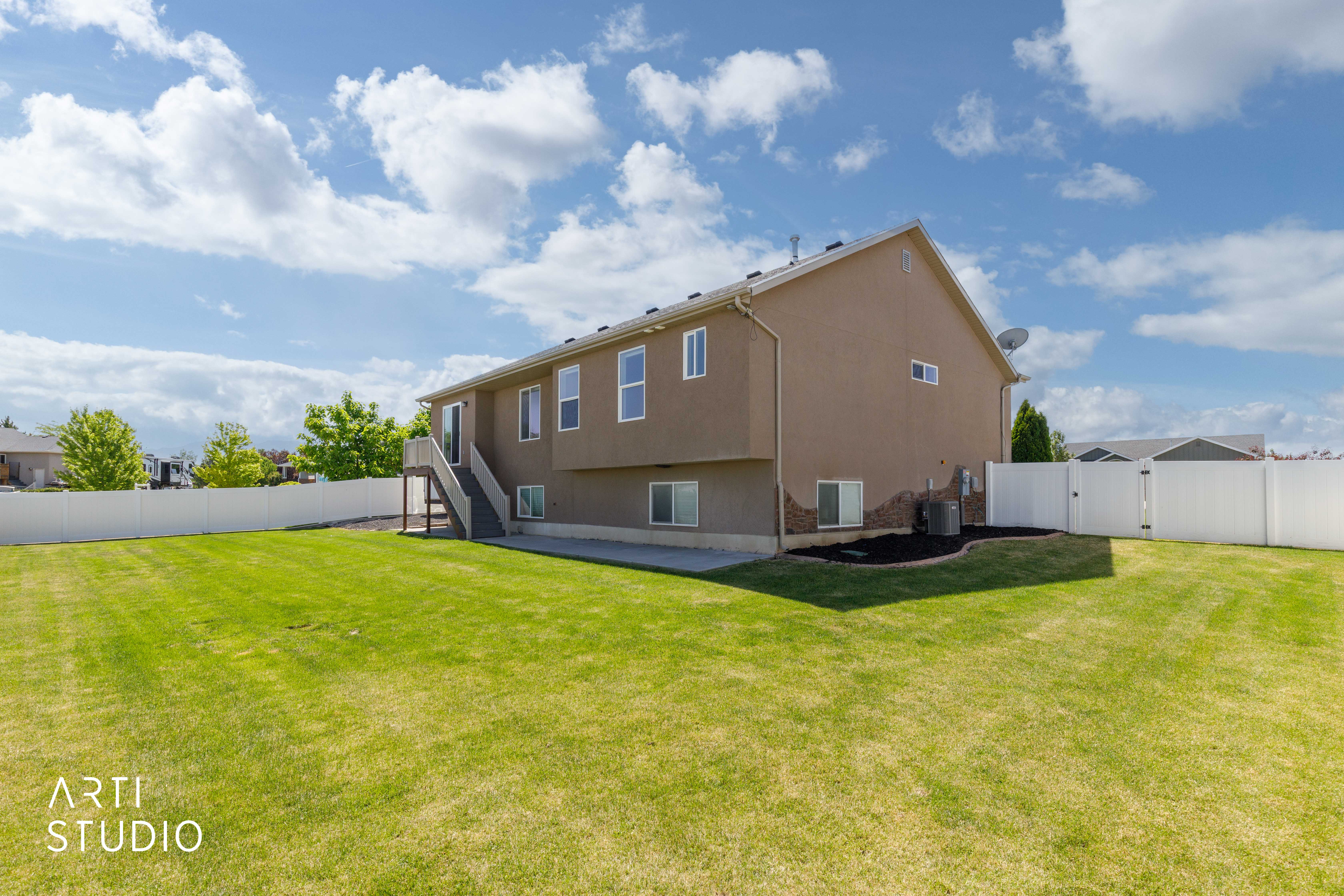 Expansive backyard featuring a manicured lawn, a full vinyl privacy fence, and a concrete patio