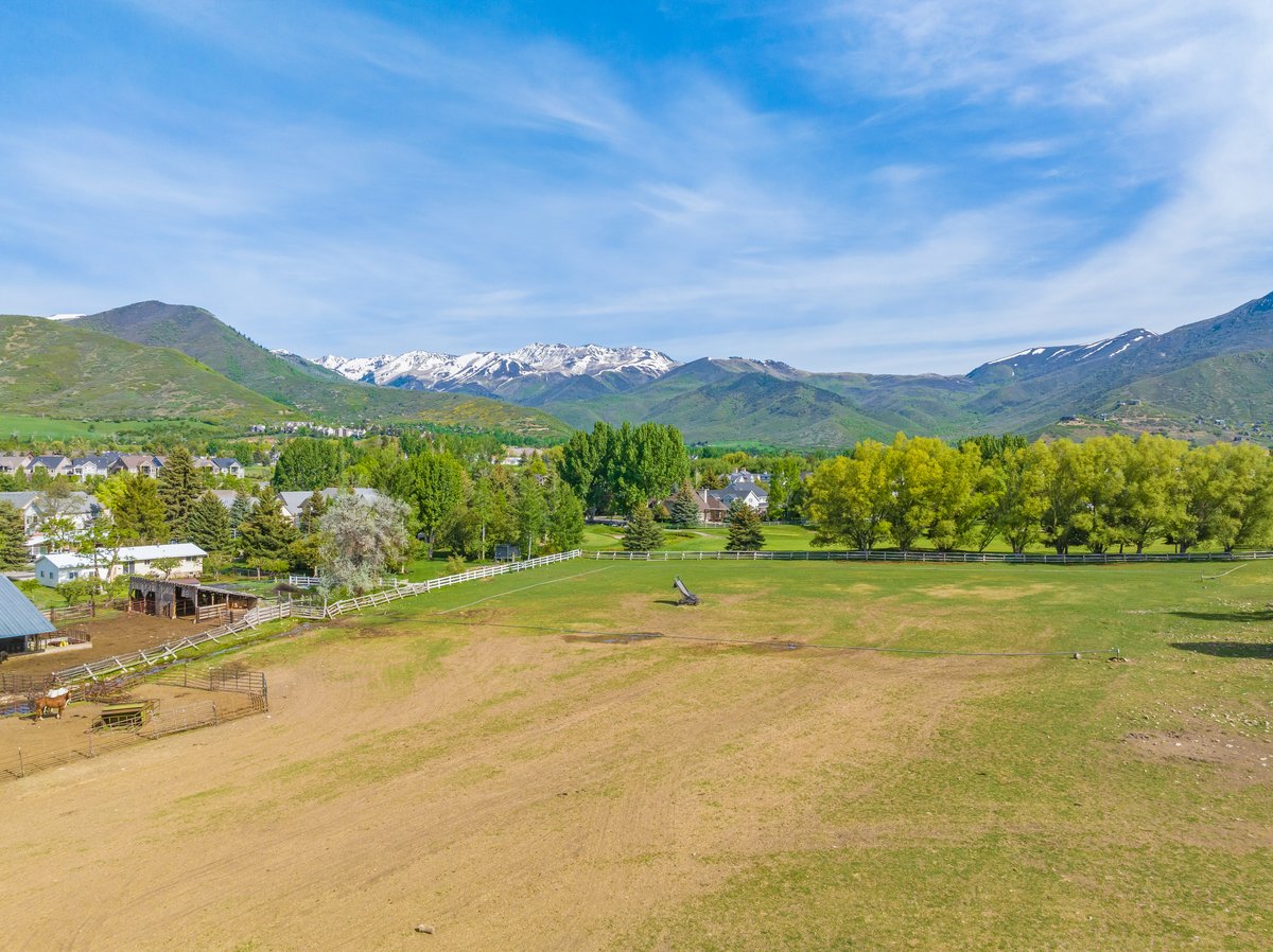 Expansive property featuring a green pasture and a white perimeter fence