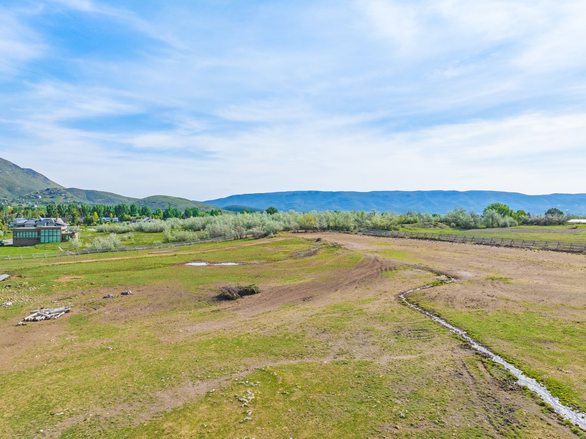 Expansive green acreage with distant mountain ranges and a winding irrigation ditch
