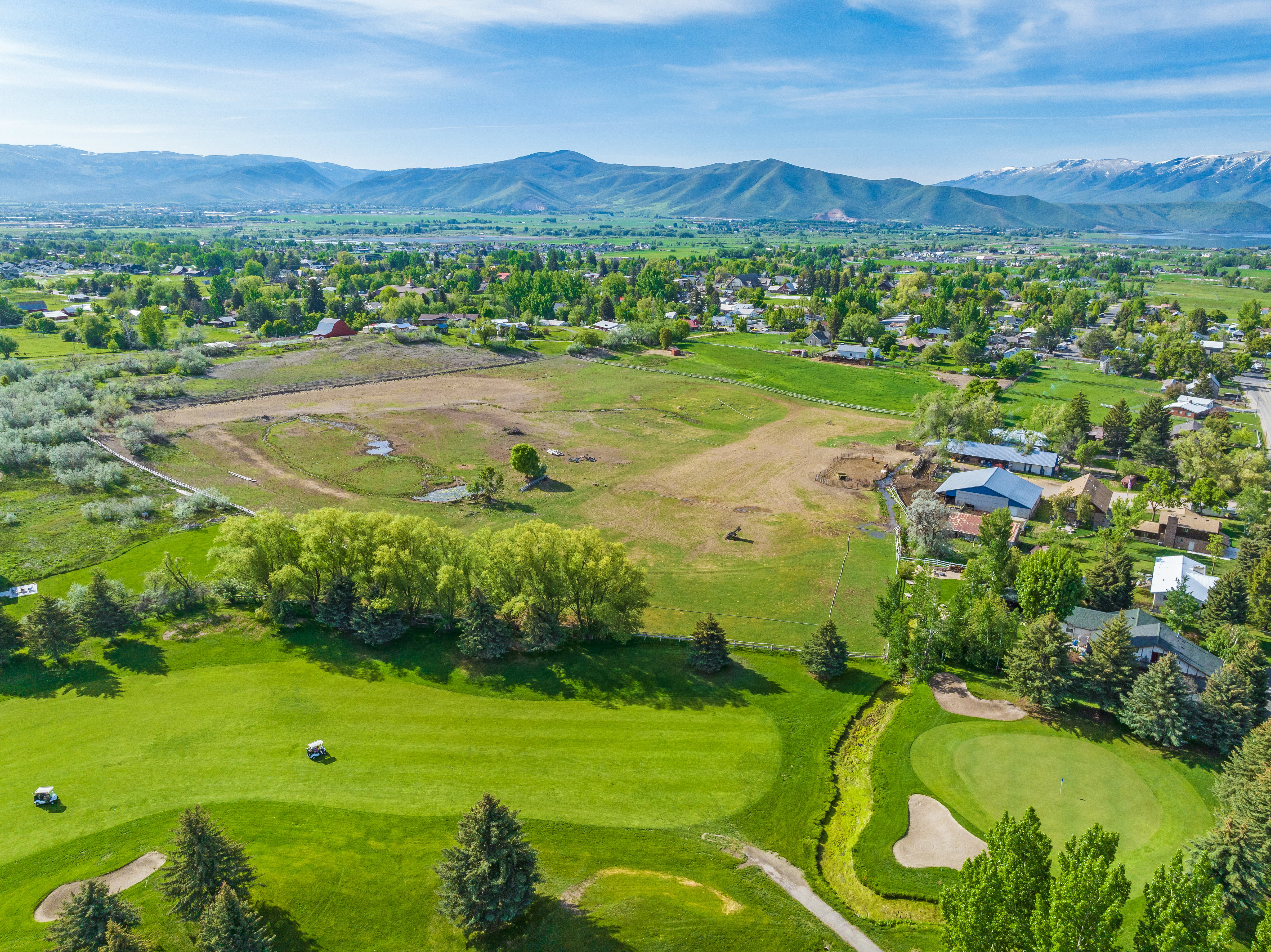 Expansive aerial view showcasing a golf course with manicured greens, sand traps, and golf carts