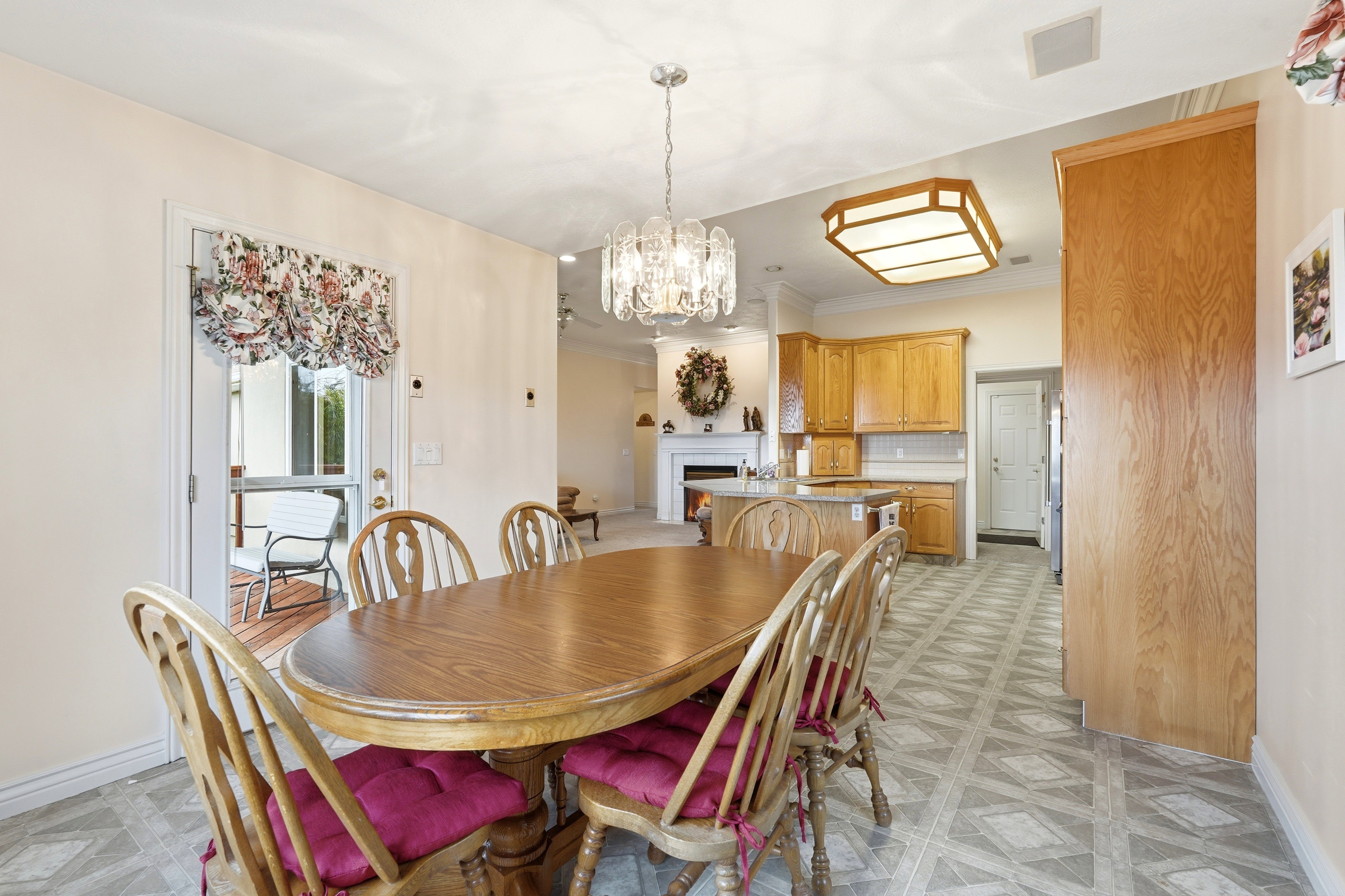 Dining area featuring a crystal chandelier, wood-finish flooring, and direct access to an outdoor patio with wood decking