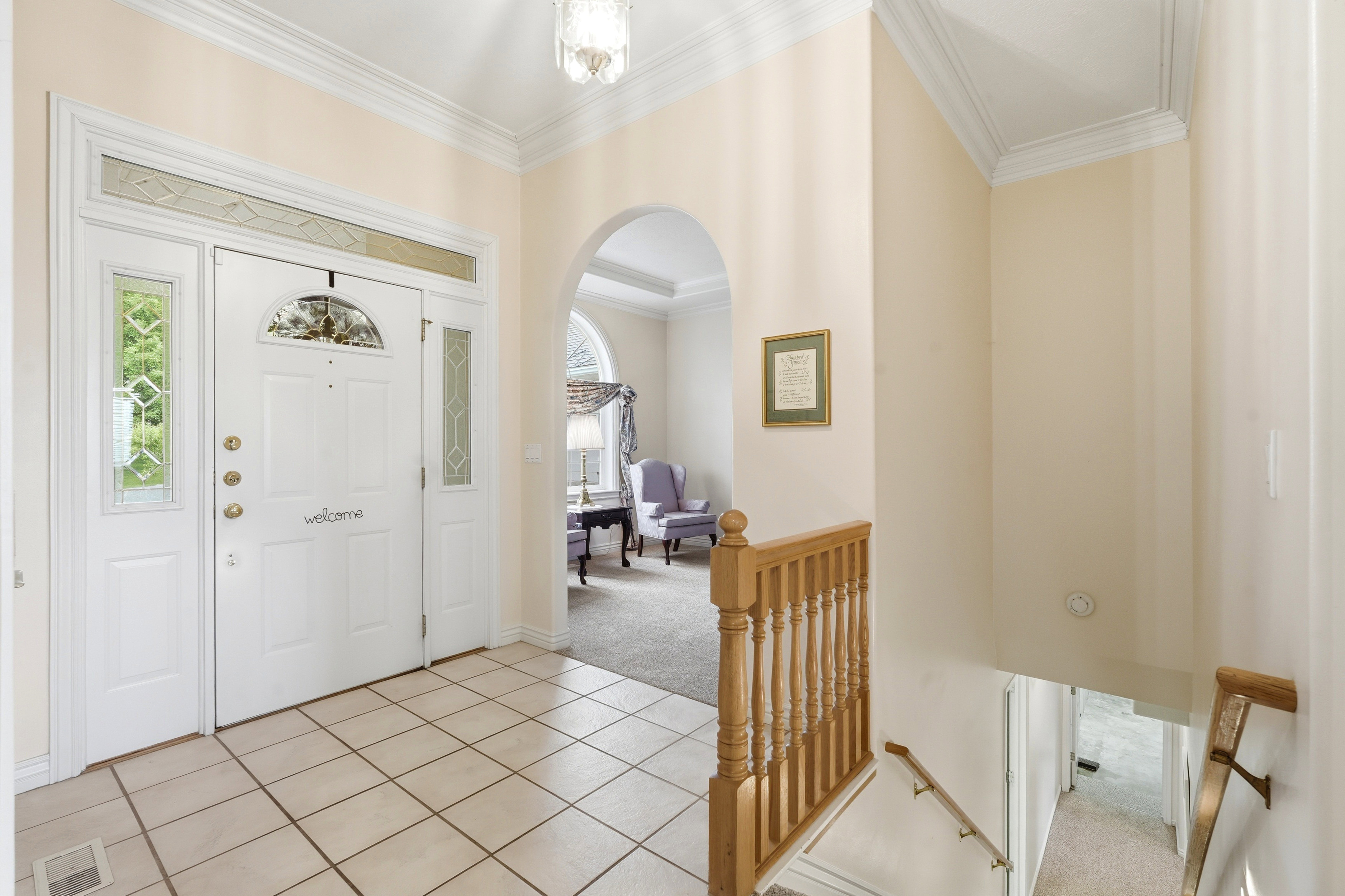 Inviting entryway featuring tile flooring, a white paneled door with decorative glass inserts, and an overhead transom window