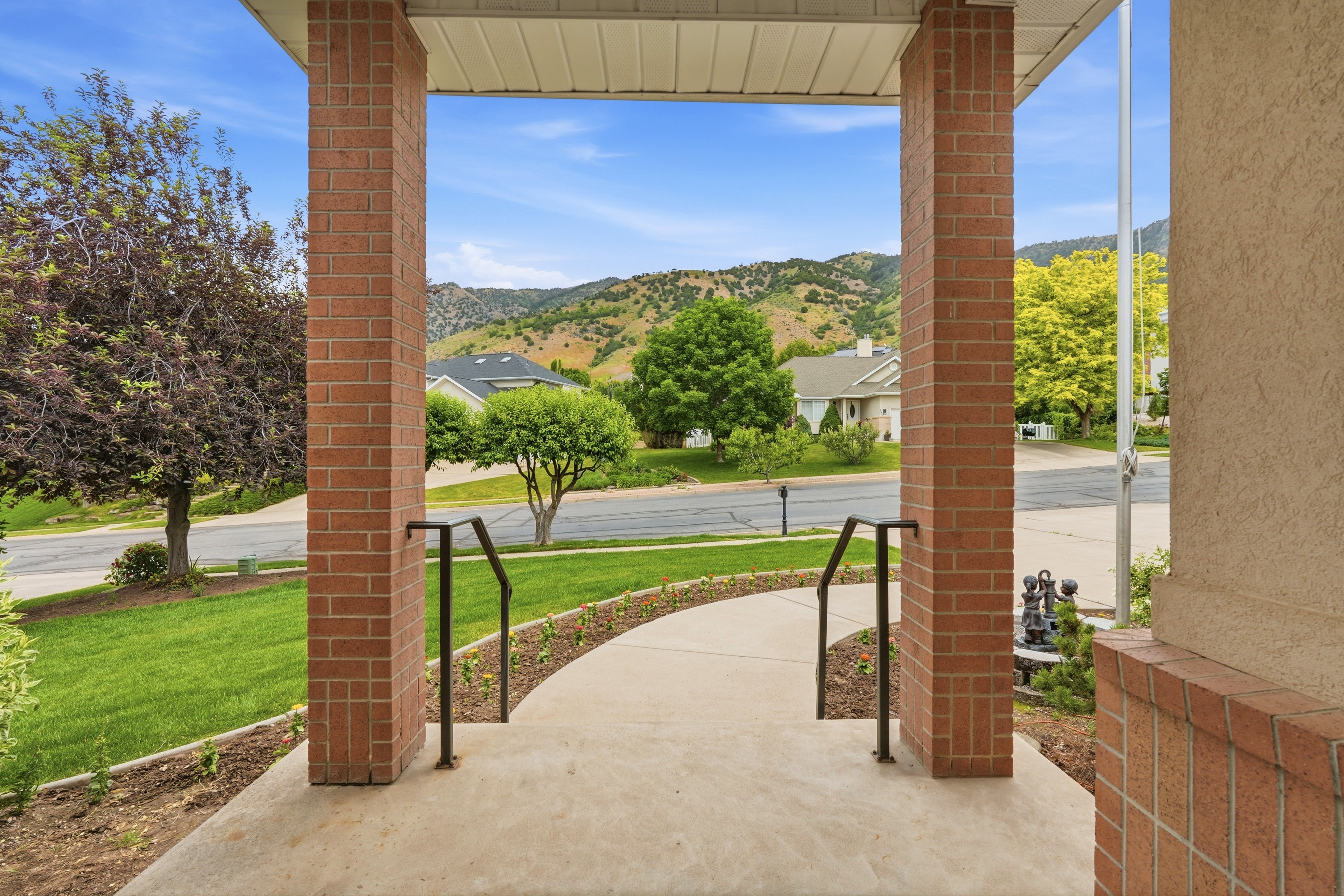 Covered front porch featuring brick columns and black metal handrails
