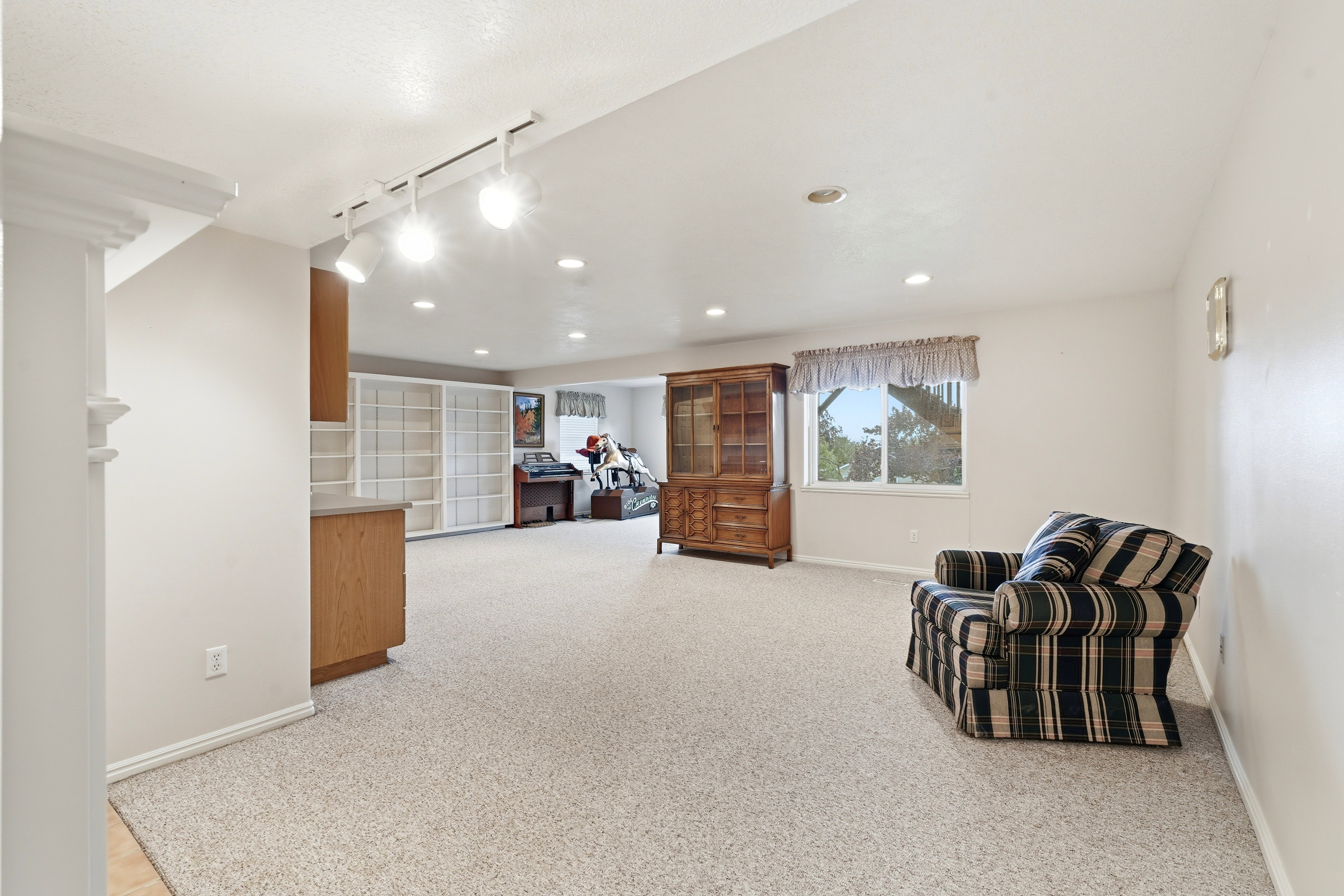 Spacious room featuring light-colored carpeting, recessed lighting, and a large window providing natural light