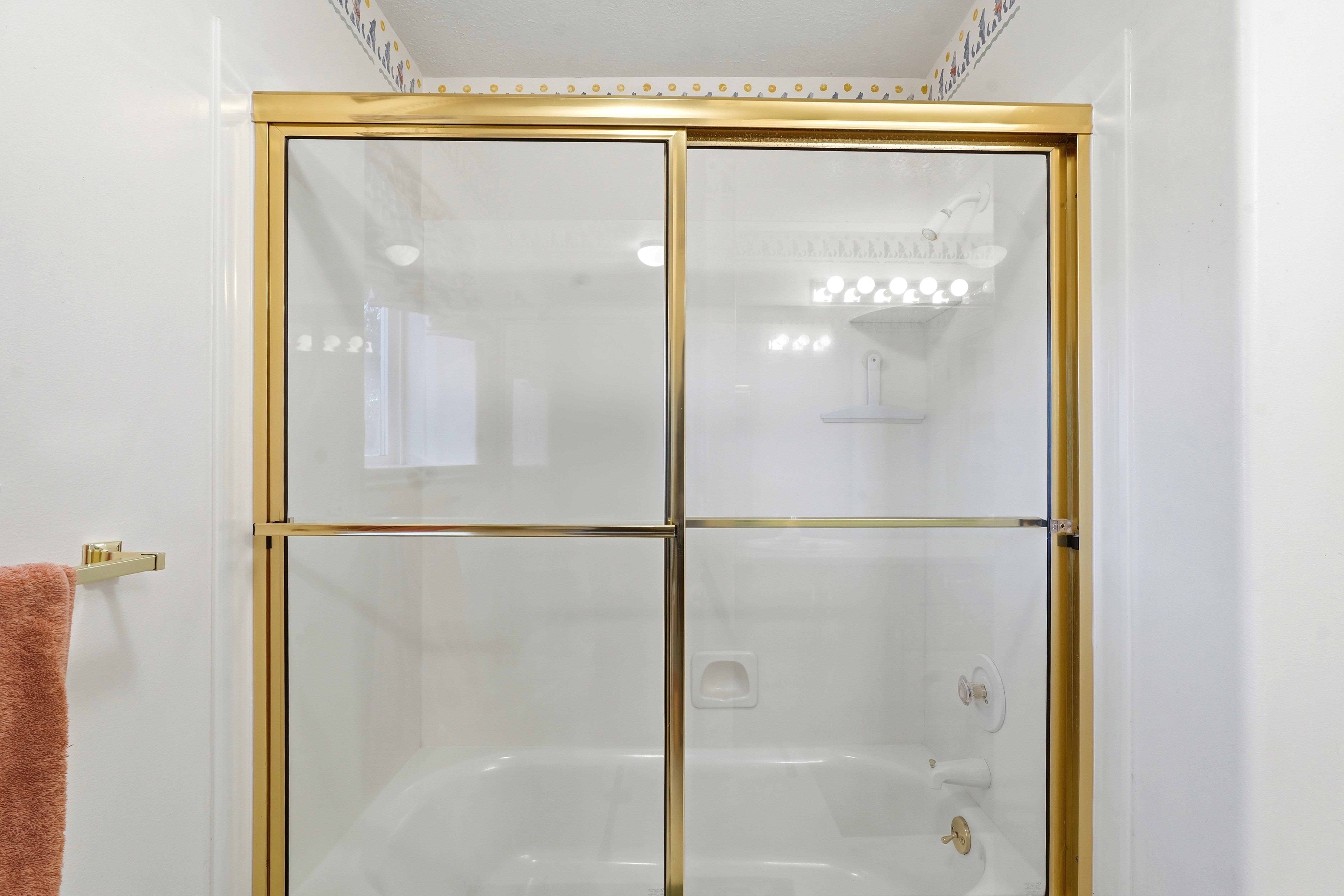 Bathtub with gold-finish sliding glass enclosure