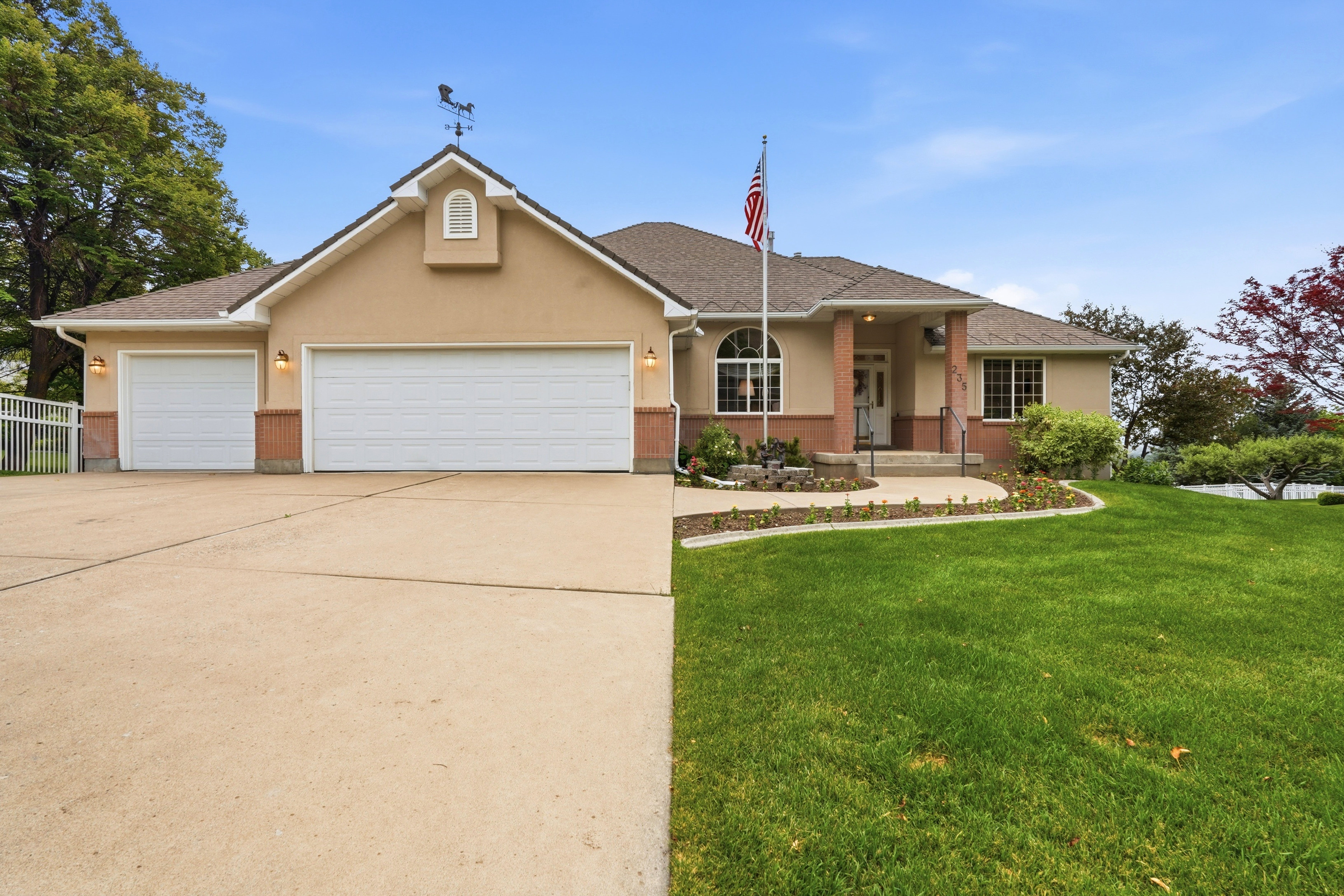 Stucco exterior with brick-finish accents, a three-car garage, and a covered front entry
