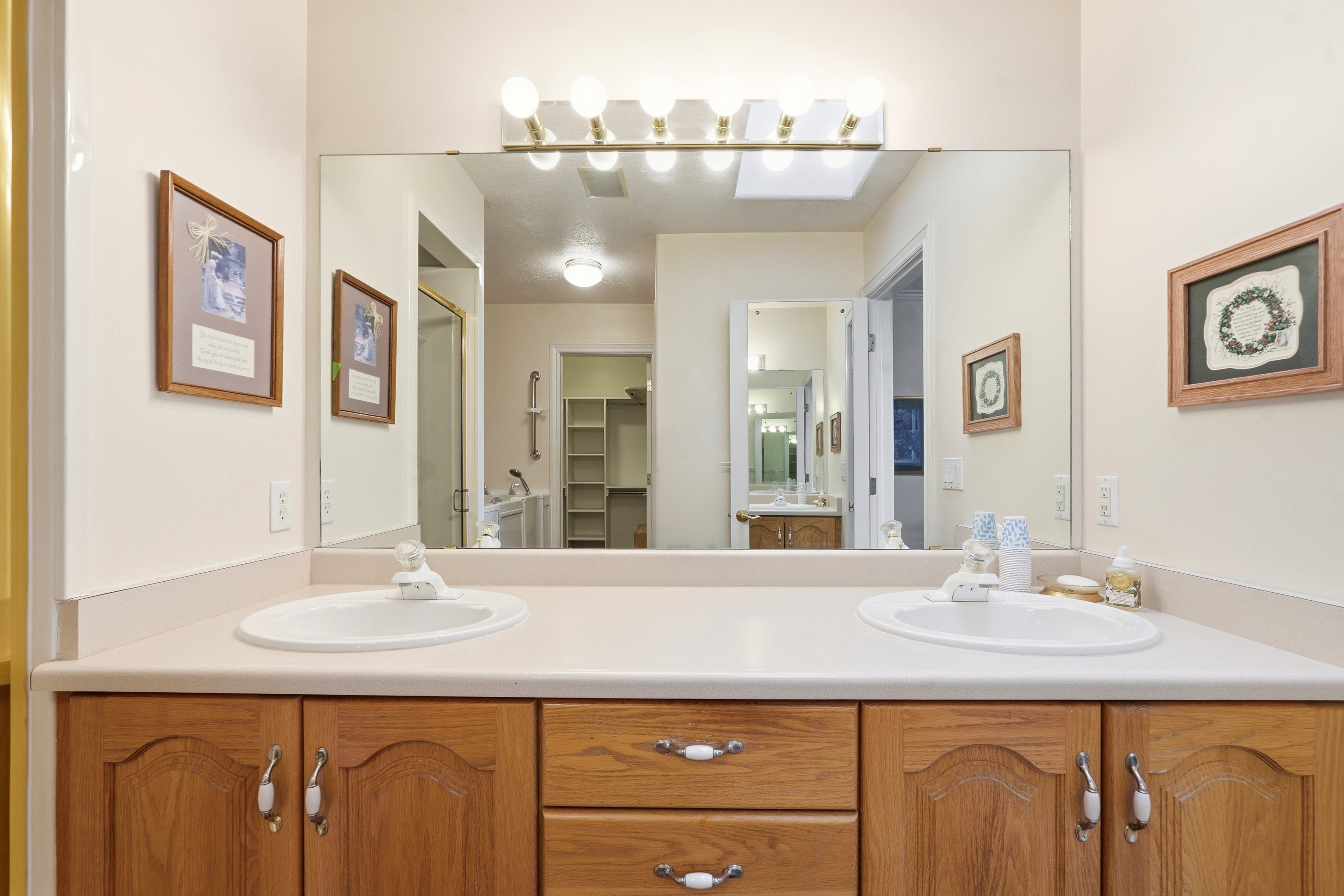Dual vanity with light wood cabinetry and white countertop