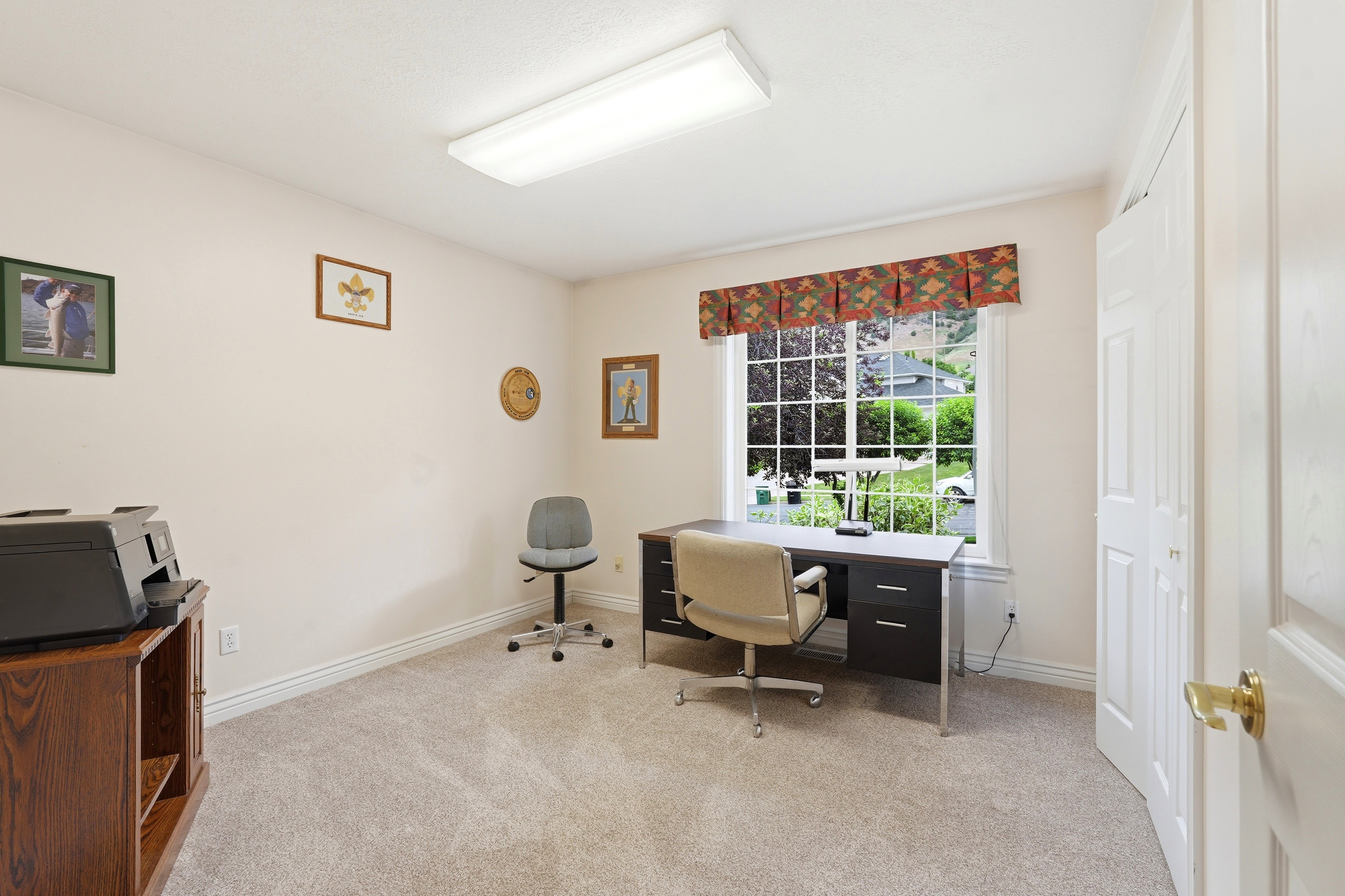 Room with neutral-toned walls, light-colored carpet, and a window with a patterned valance