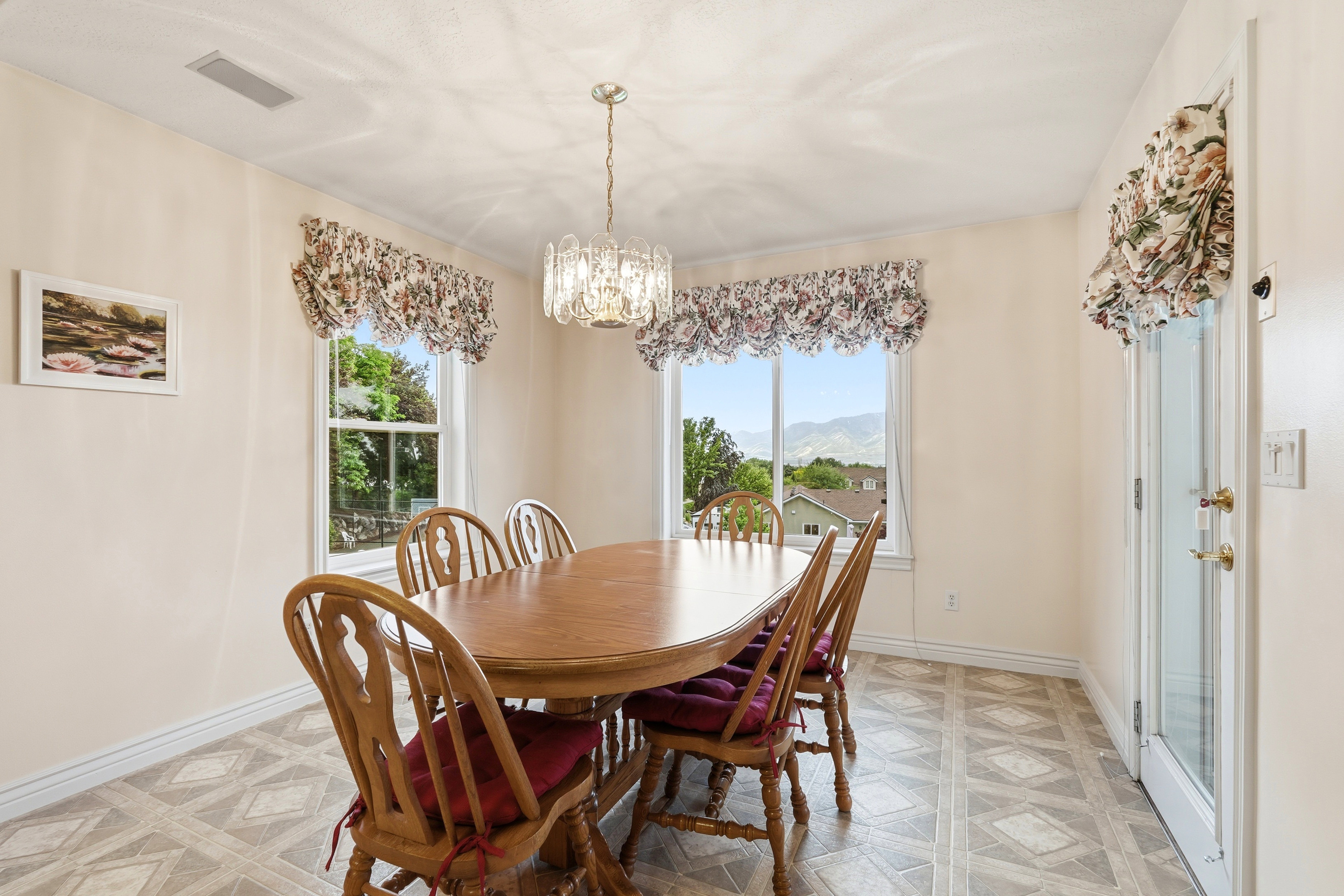 Dining area featuring patterned flooring, multiple windows, a glass-paneled door, and a decorative chandelier