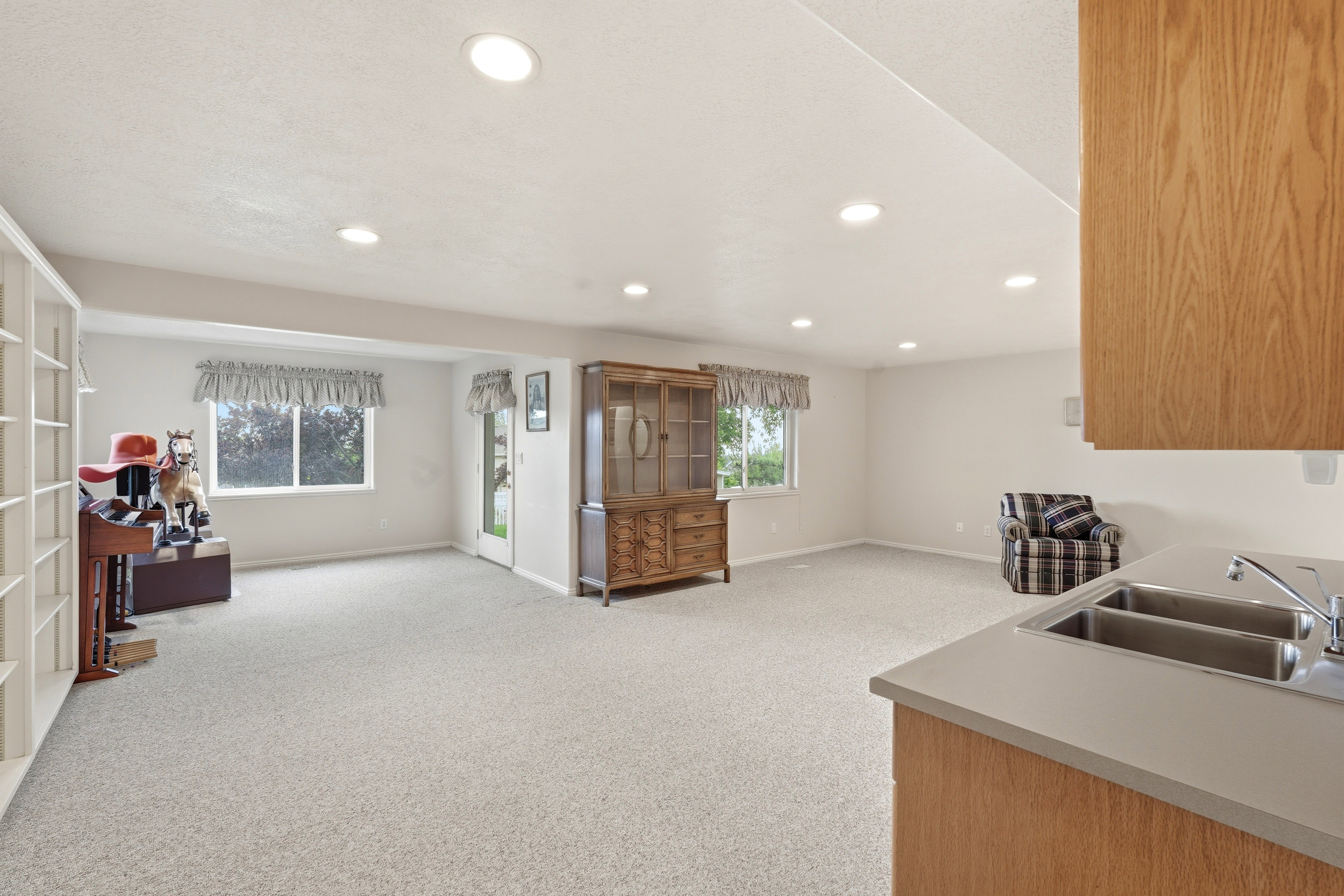 Spacious room featuring light-colored carpeting, recessed ceiling lighting, and multiple windows