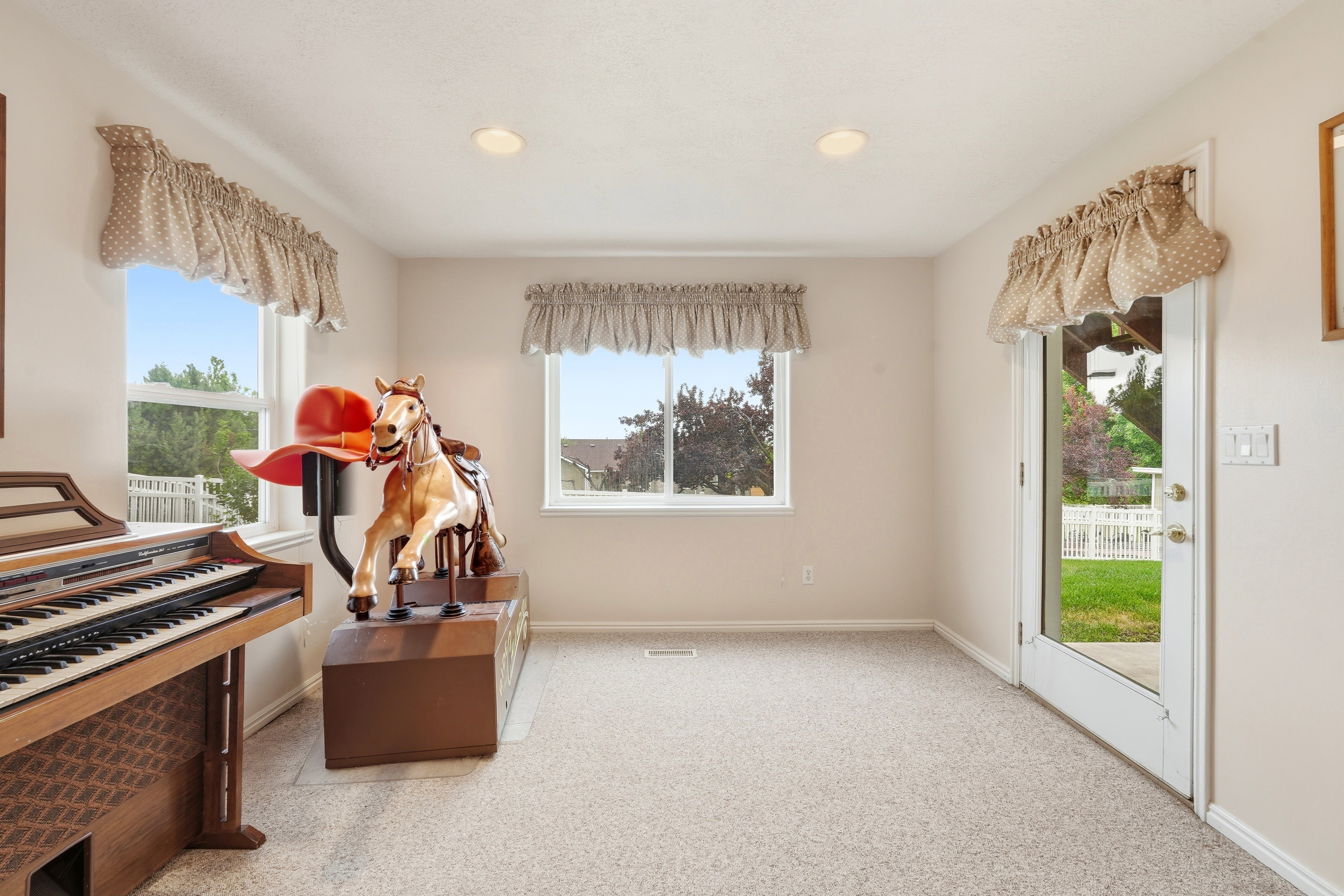 Carpeted room featuring multiple windows, a glass-paned door, recessed lighting, and light-toned wall finishes