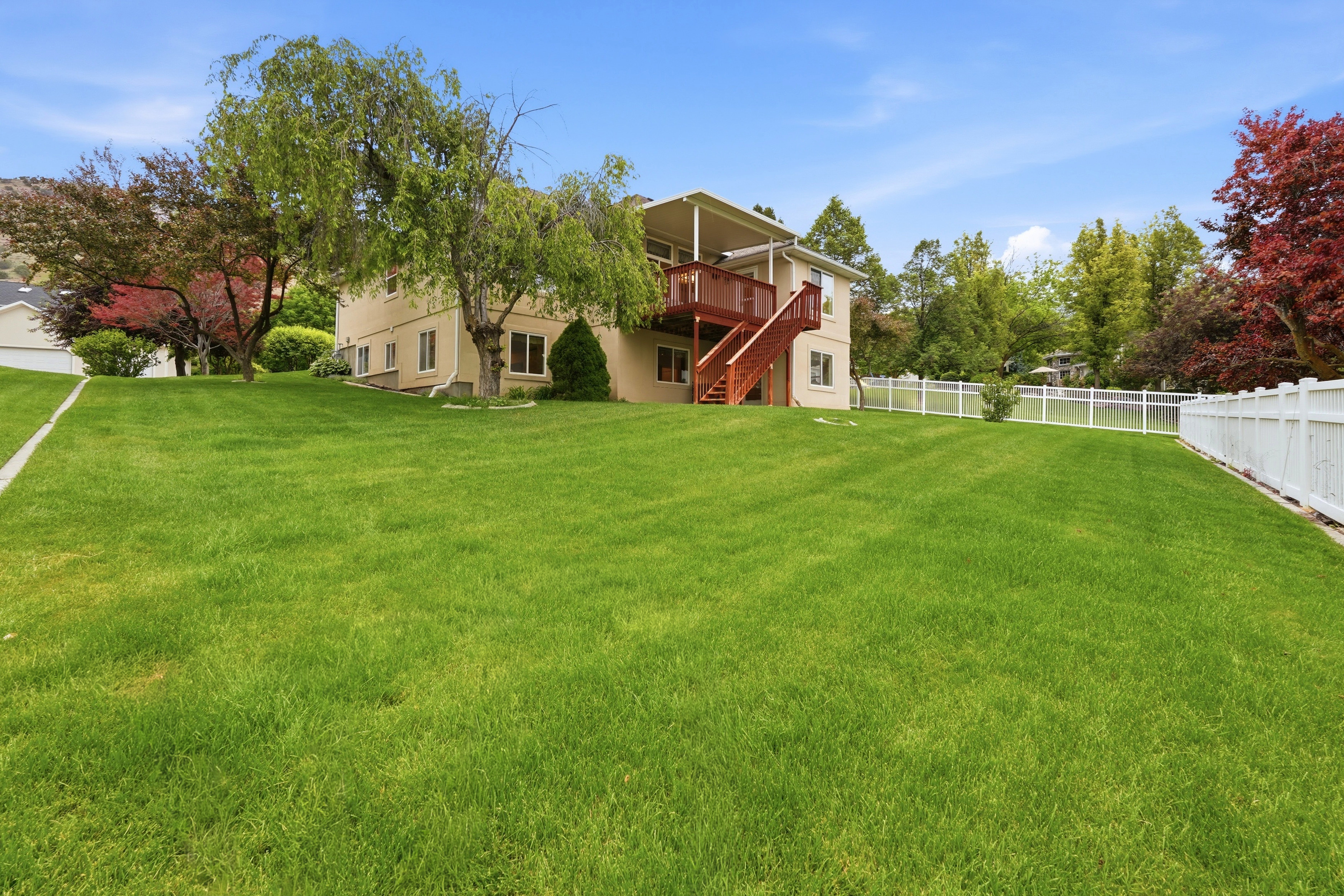 Expansive grassy yard surrounding a two-story residence with a beige exterior