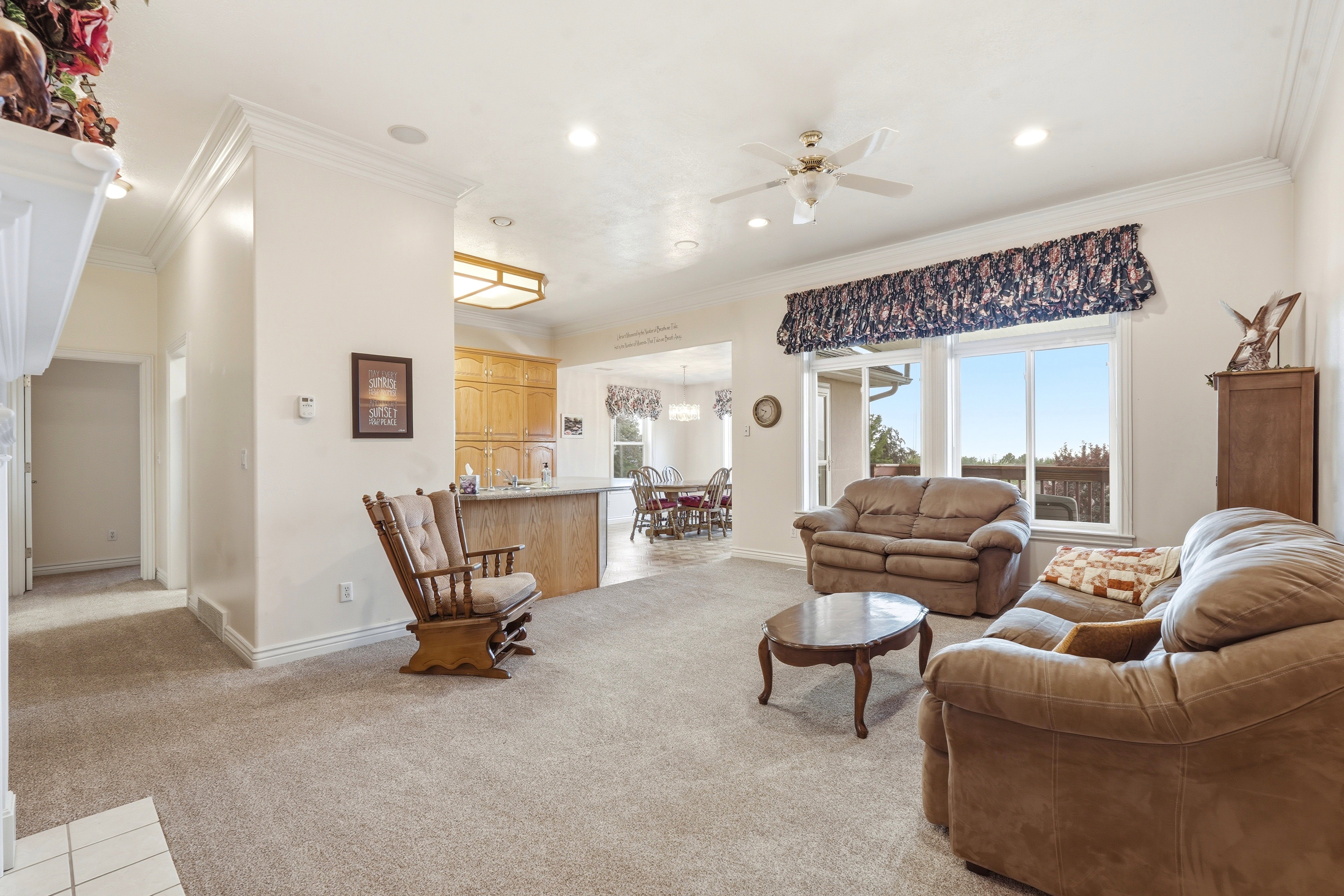 Spacious living area featuring neutral carpeting and crown molding