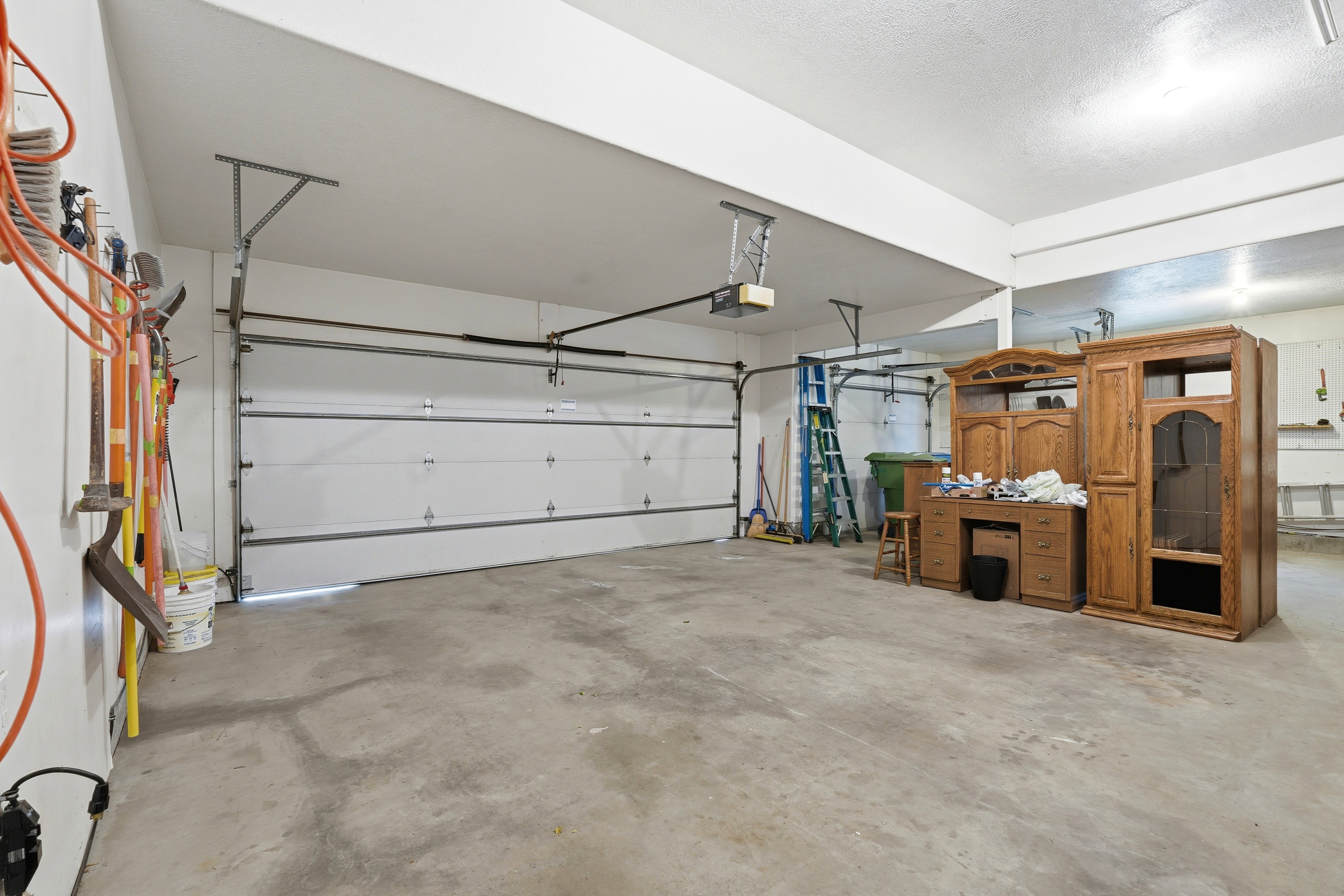 Spacious garage with concrete flooring, two overhead doors, and overhead lighting