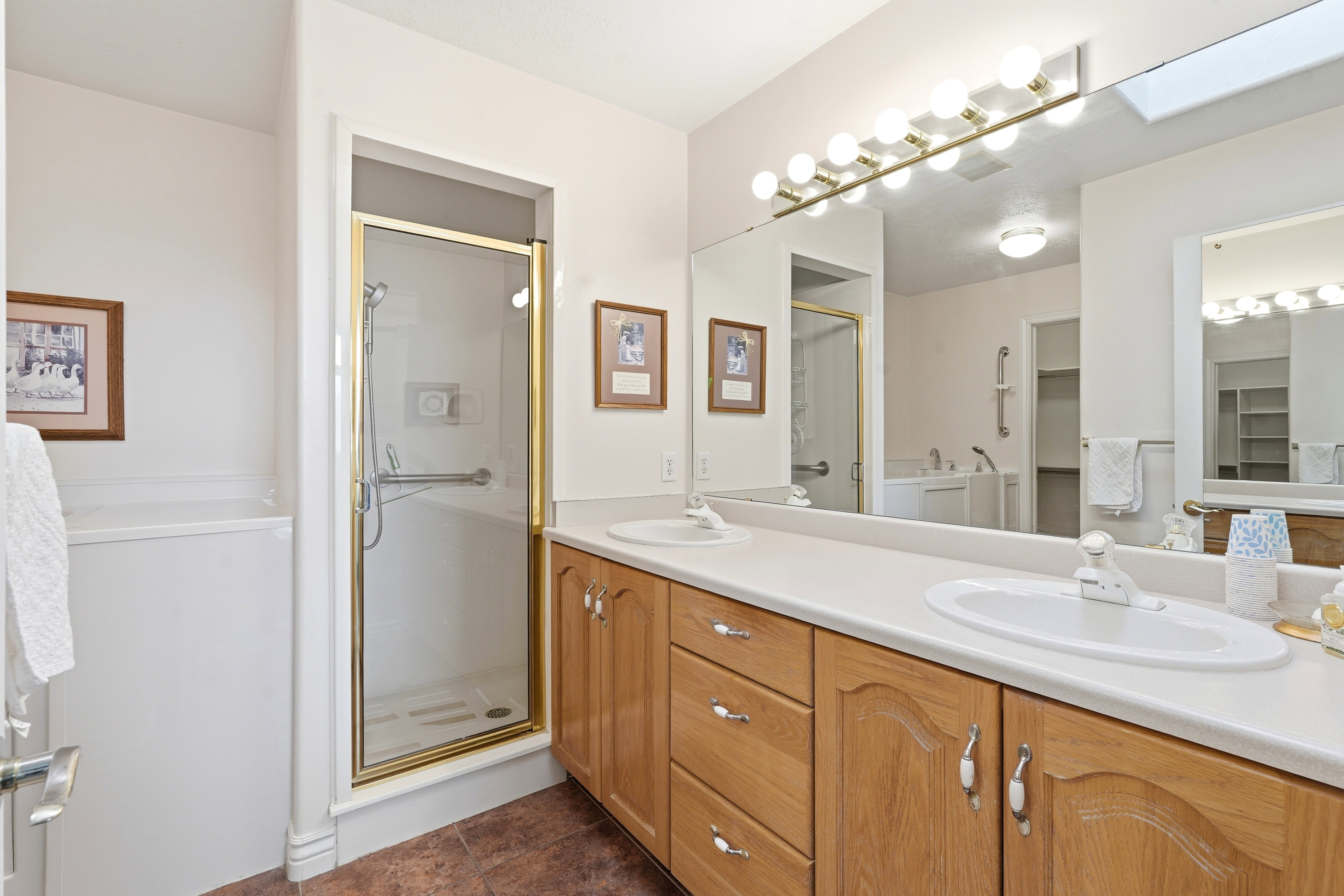 Bathroom with a double vanity featuring light wood-finish cabinetry and white countertops