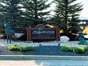 Wood-framed entrance sign featuring carved lettering, flanked by a bronze deer statue and a bronze flying geese sculpture