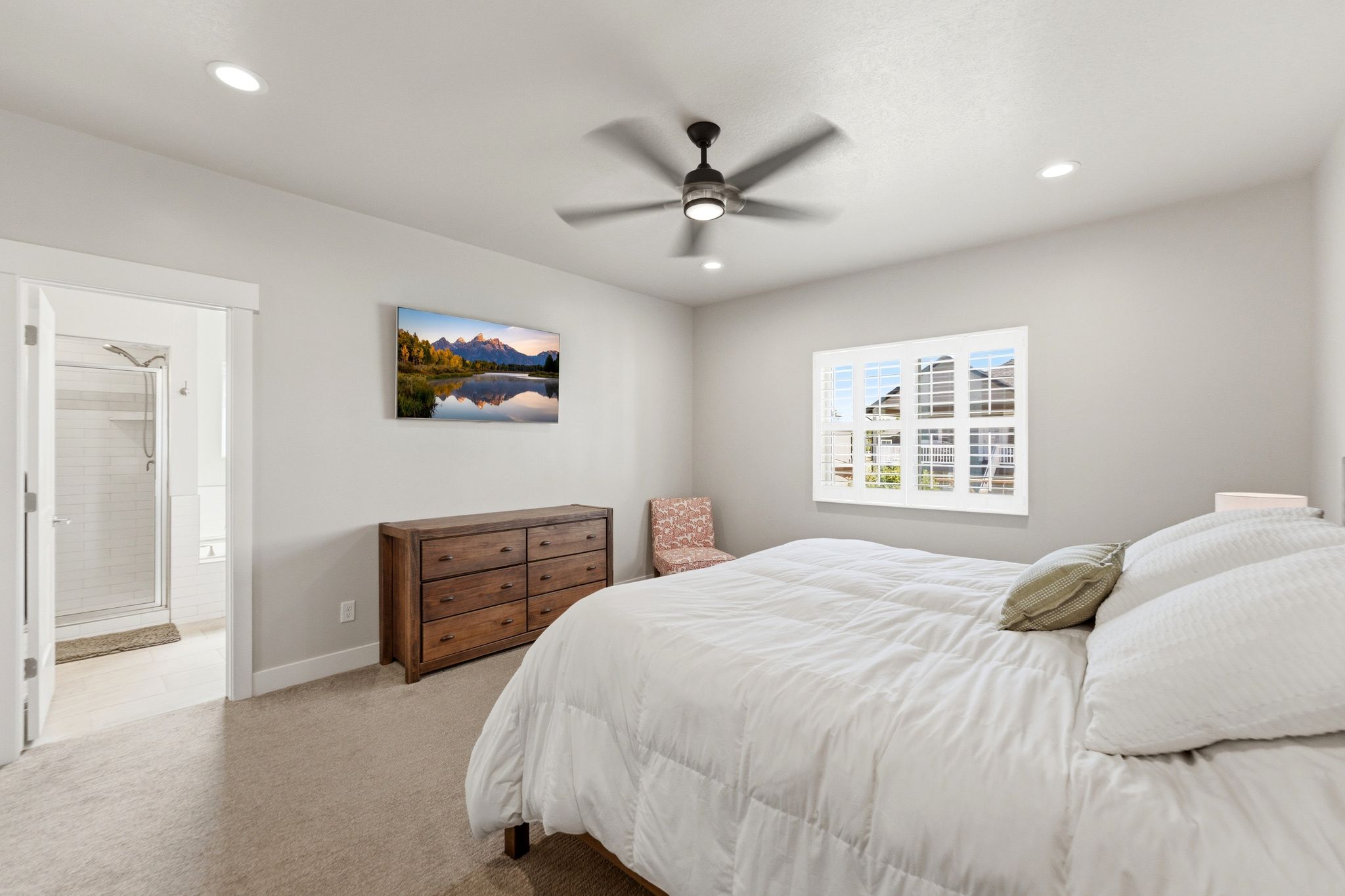 Comfortable primary bedroom with fan and ensuite bathroom.
