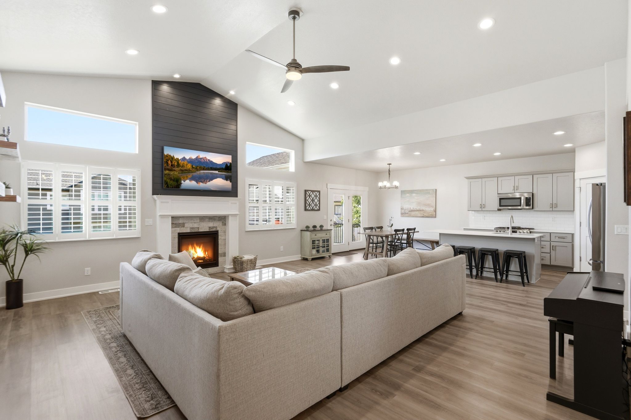 Vaulted great room featuring a shiplap fireplace surround, built-in fireplace, and expansive windows with plantation shutters.