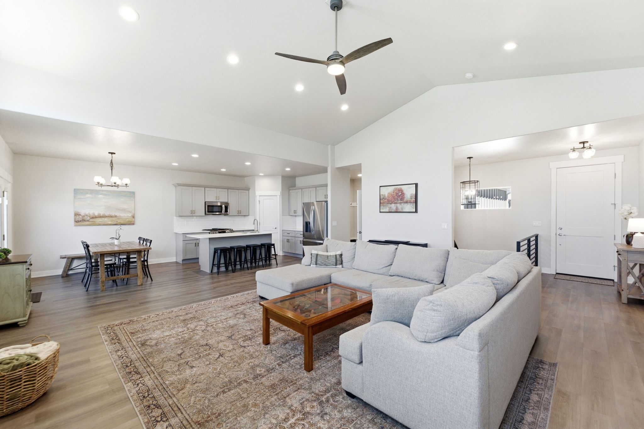 Open-concept living space featuring wood-finish flooring, recessed lighting, and a vaulted ceiling with a ceiling fan.