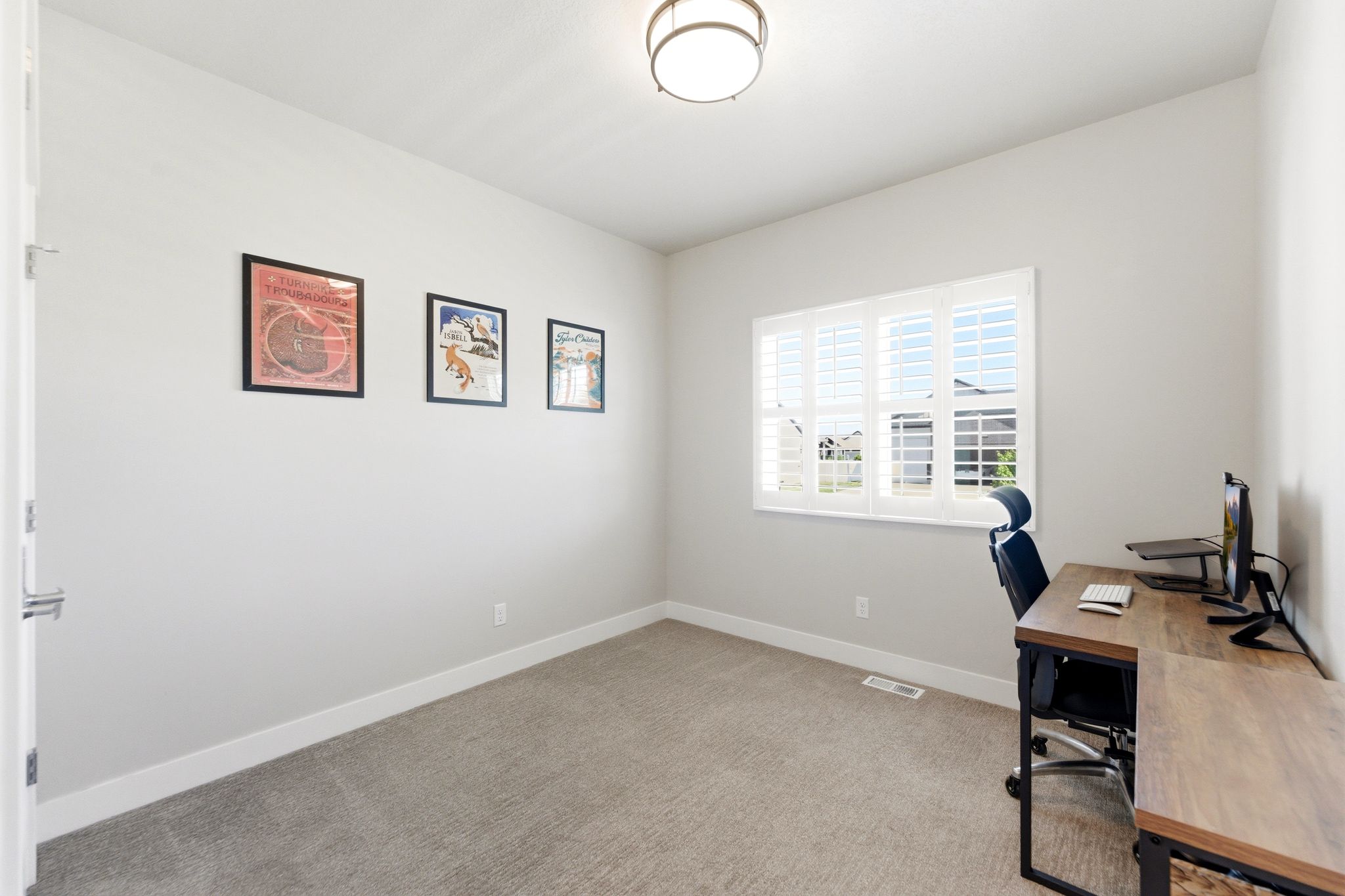 Bedroom #2 with light gray walls, white baseboards, and a single window featuring white plantation shutters.
