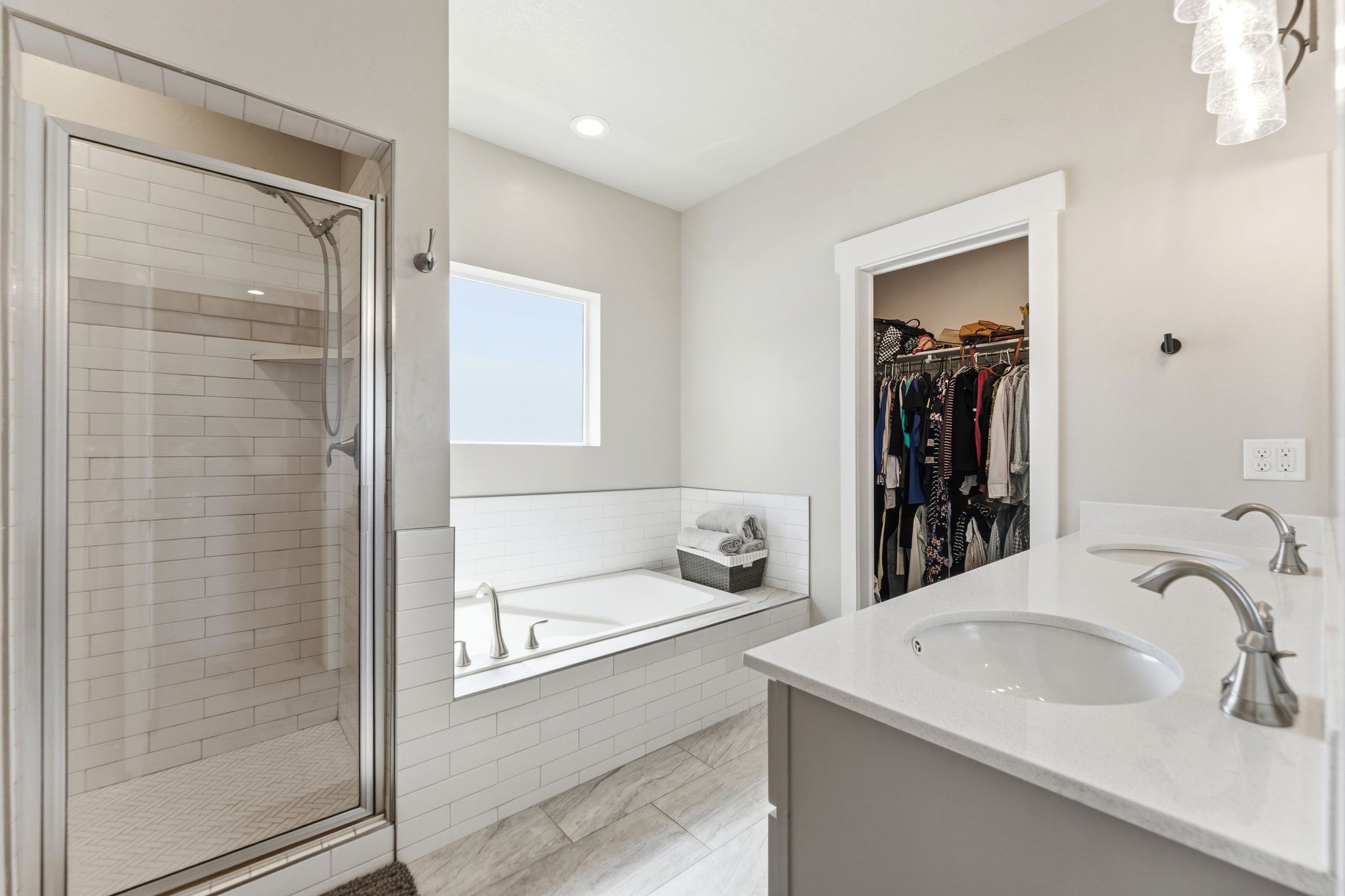 Spacious bathroom featuring a glass-enclosed shower, separate soaking tub, and walk in closet.