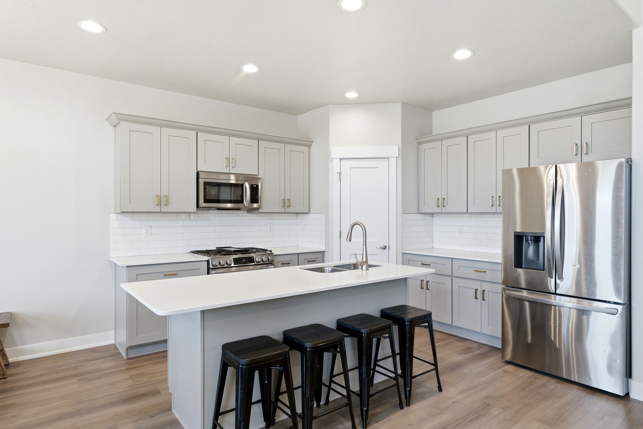 Kitchen featuring light gray cabinetry, white countertops, stainless steel appliances, and a subway tile backsplash.