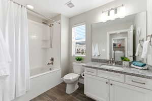 Contemporary bathroom featuring a white subway tile tub surround with integrated shelving, a single vanity with stone countertop, wood-finish flooring, a window with horizontal blinds, and a large wall-mounted mirror