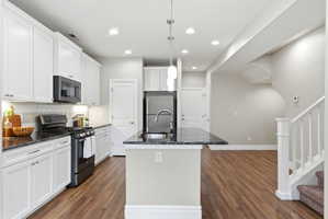 Kitchen featuring white cabinetry, dark stone countertops, stainless steel appliances, and a tile backsplash