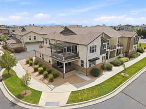 Multi-level townhouse exterior featuring a private balcony with a pergola, ground-level patio, and a two-car garage