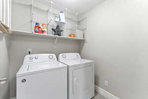 Dedicated utility area featuring white appliances, a wall-mounted shelf, and wire storage cubbies