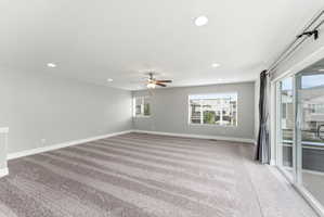 Spacious room featuring neutral carpeting, recessed lighting, and a ceiling fan
